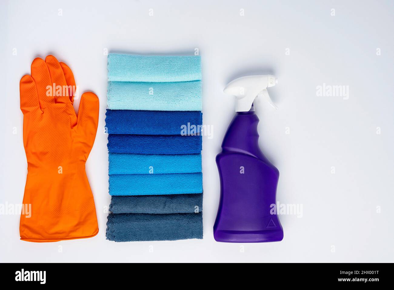 Une bouteille violette de nettoyant avec un spray et des chiffons de nettoyage colorés sur fond blanc . Outils de nettoyage à l'eau Banque D'Images