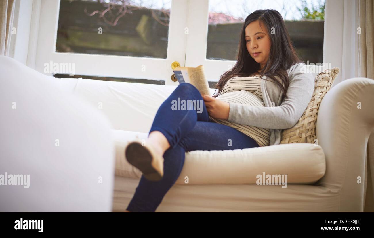 Le congé de maternité signifie un peu de temps pour elle pour se détendre. Photo d'une femme enceinte lisant un livre à la maison. Banque D'Images