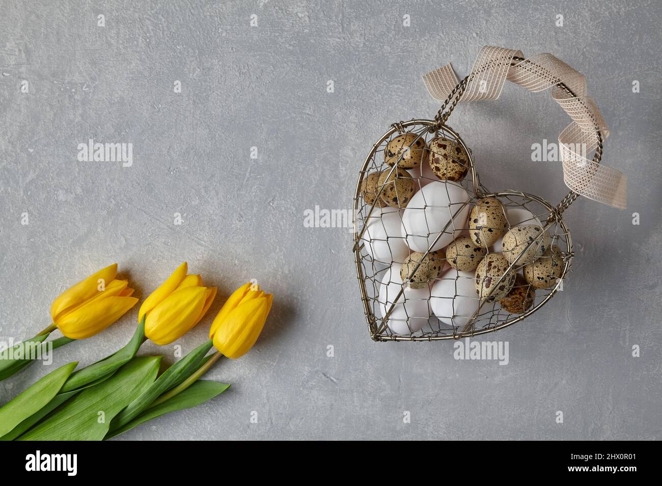 Œufs de poulet et de caille dans un panier en fil métallique tissé en forme de cœur Banque D'Images