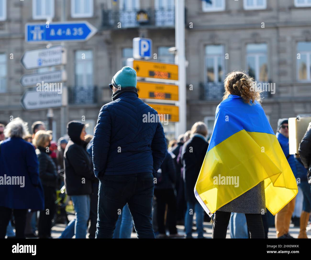 Vue arrière de la femme portant le drapeau ukrainien marchant dans la rue à la protestation devant le consulat russe solidarité Ukrainiens contre la guerre après l'invasion russe Banque D'Images