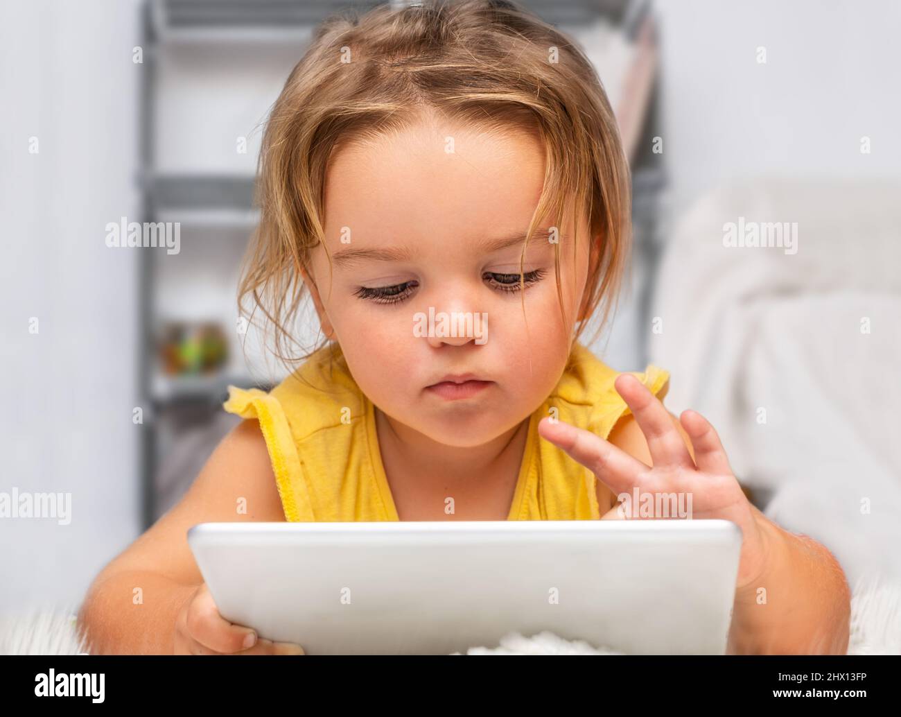 L'enfant est allongé sur le sol et utilise une tablette dans le salon Banque D'Images