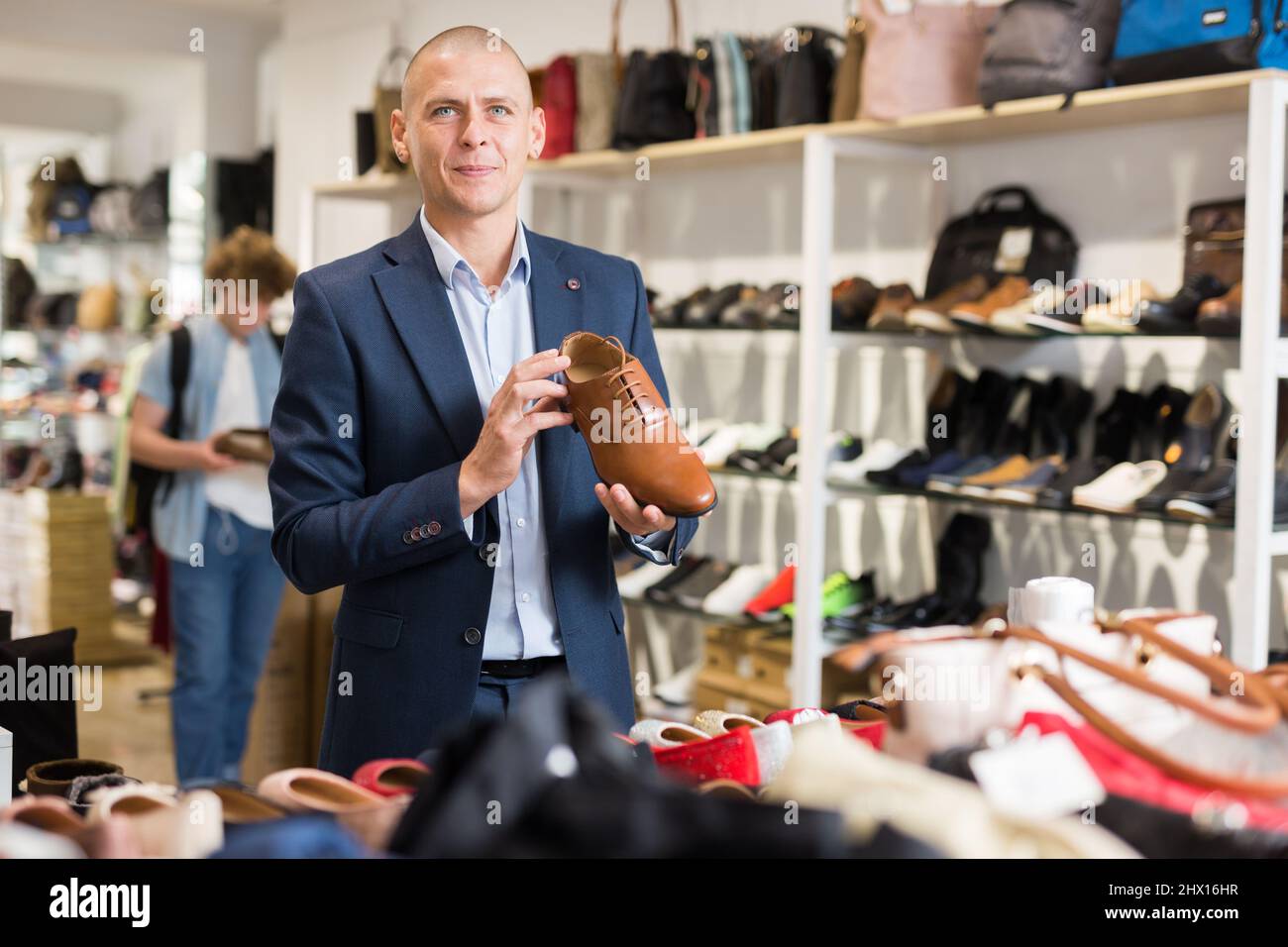 Homme souriant à la recherche de chaussures classiques dans un magasin de chaussures Banque D'Images