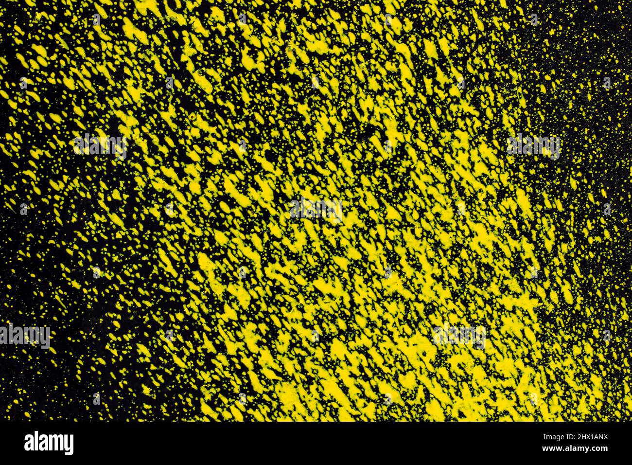 aérosol de peinture jaune sur une surface métallique noire. arrière-plan abstrait, texture Banque D'Images