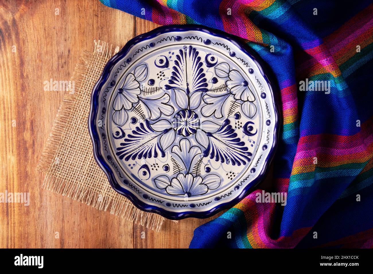 Cuisine mexicaine fond, tissus traditionnels colorés et assiette vide de style talavera sur une table rustique en bois. Pose à plat Banque D'Images