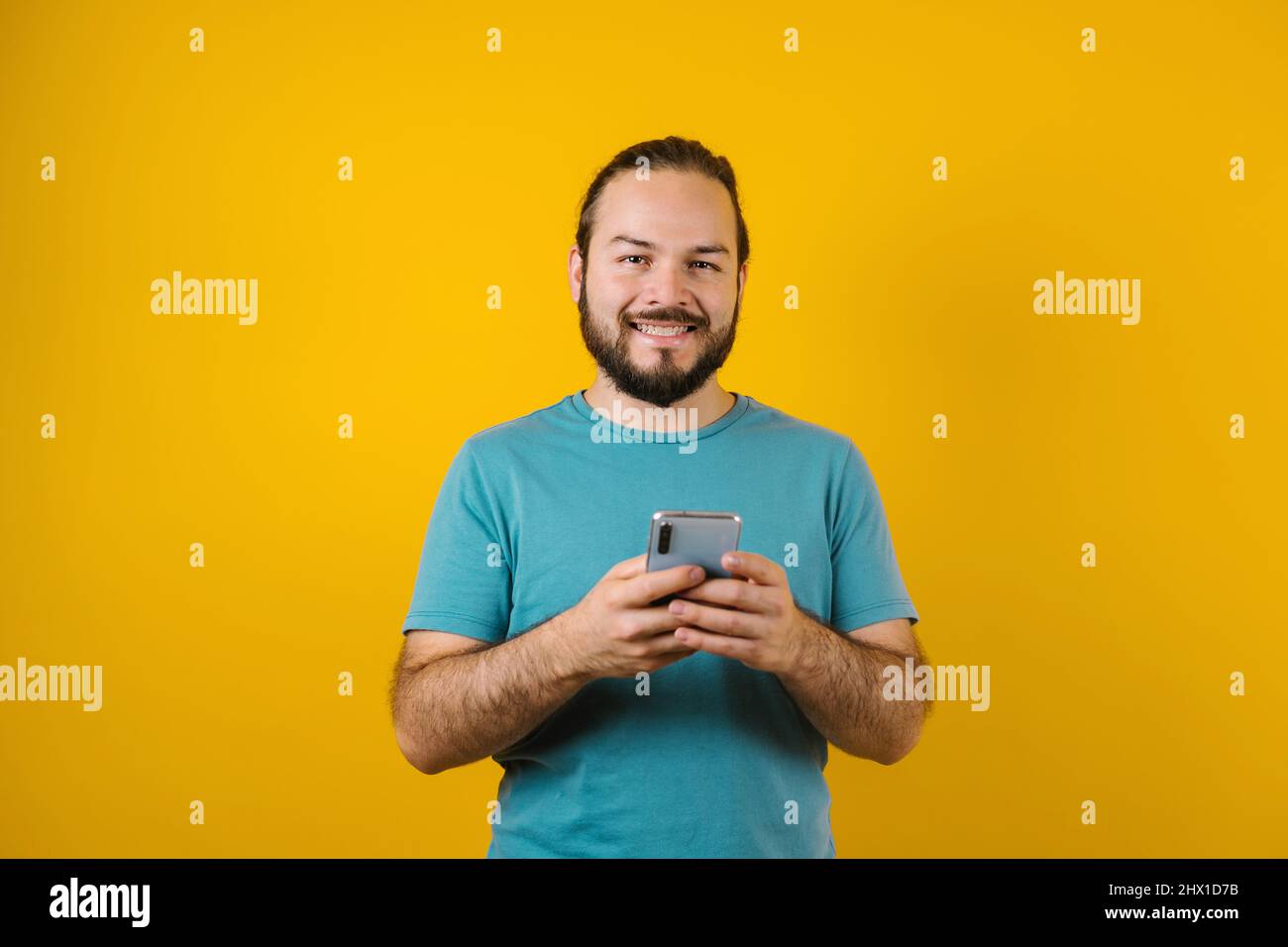 Jeune hispanique utilisant un téléphone mobile sur fond jaune au Mexique Amérique latine Banque D'Images Jeune hispanique utilisant un téléphone mobile sur fond jaune au Mexique Amérique latine Banque D'Images