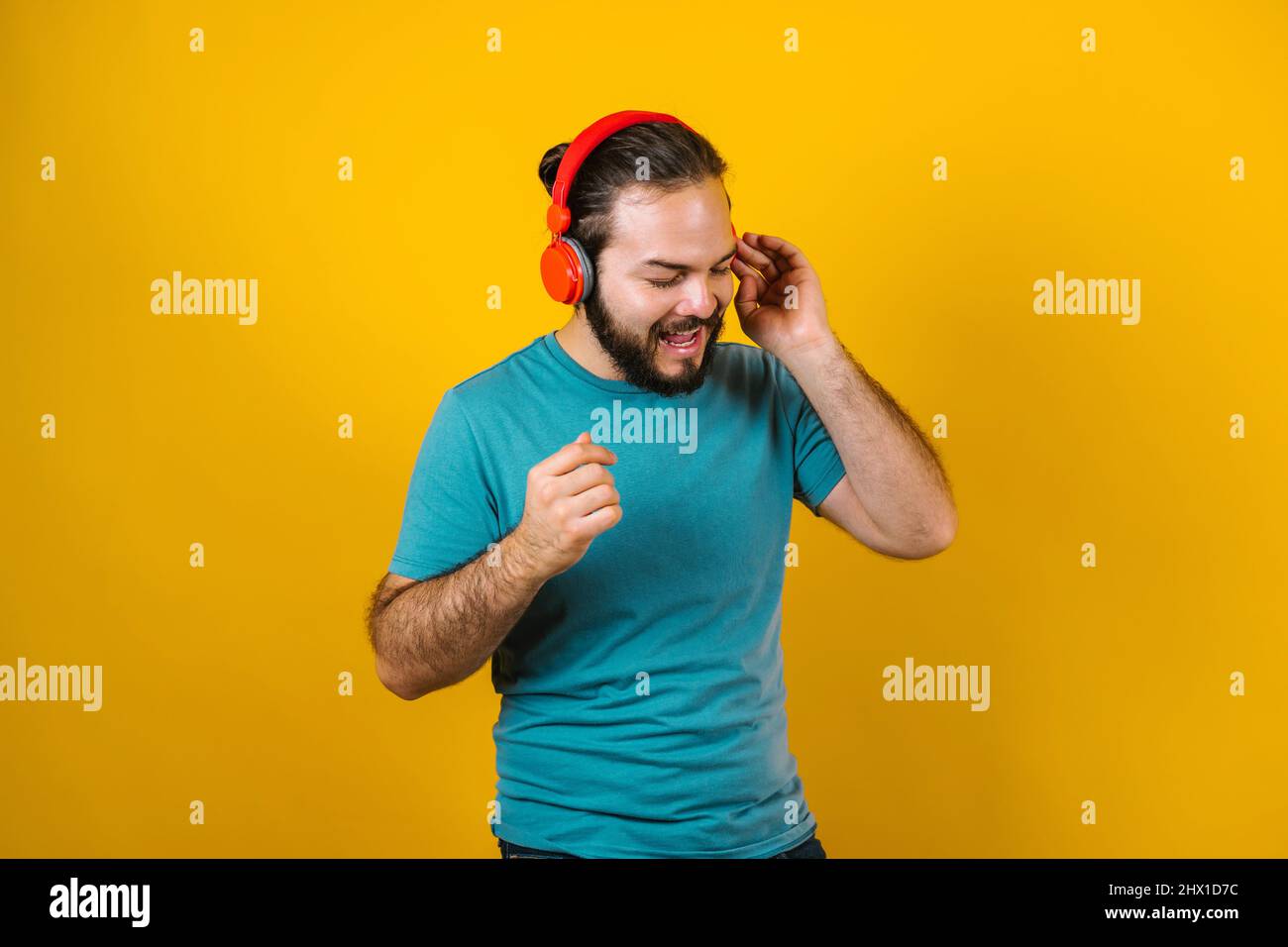Portrait d'un jeune homme hispanique avec écouteurs, danse et musique d'écoute sur fond jaune au Mexique Amérique latine Banque D'Images Portrait d'un jeune homme hispanique avec écouteurs, danse et musique d'écoute sur fond jaune au Mexique Amérique latine Banque D'Images
