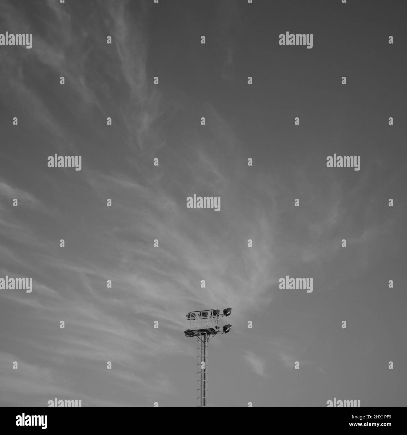 Lampadaire de stade dans un ciel nuageux spectaculaire - Photographie d'art noir et blanc Banque D'Images