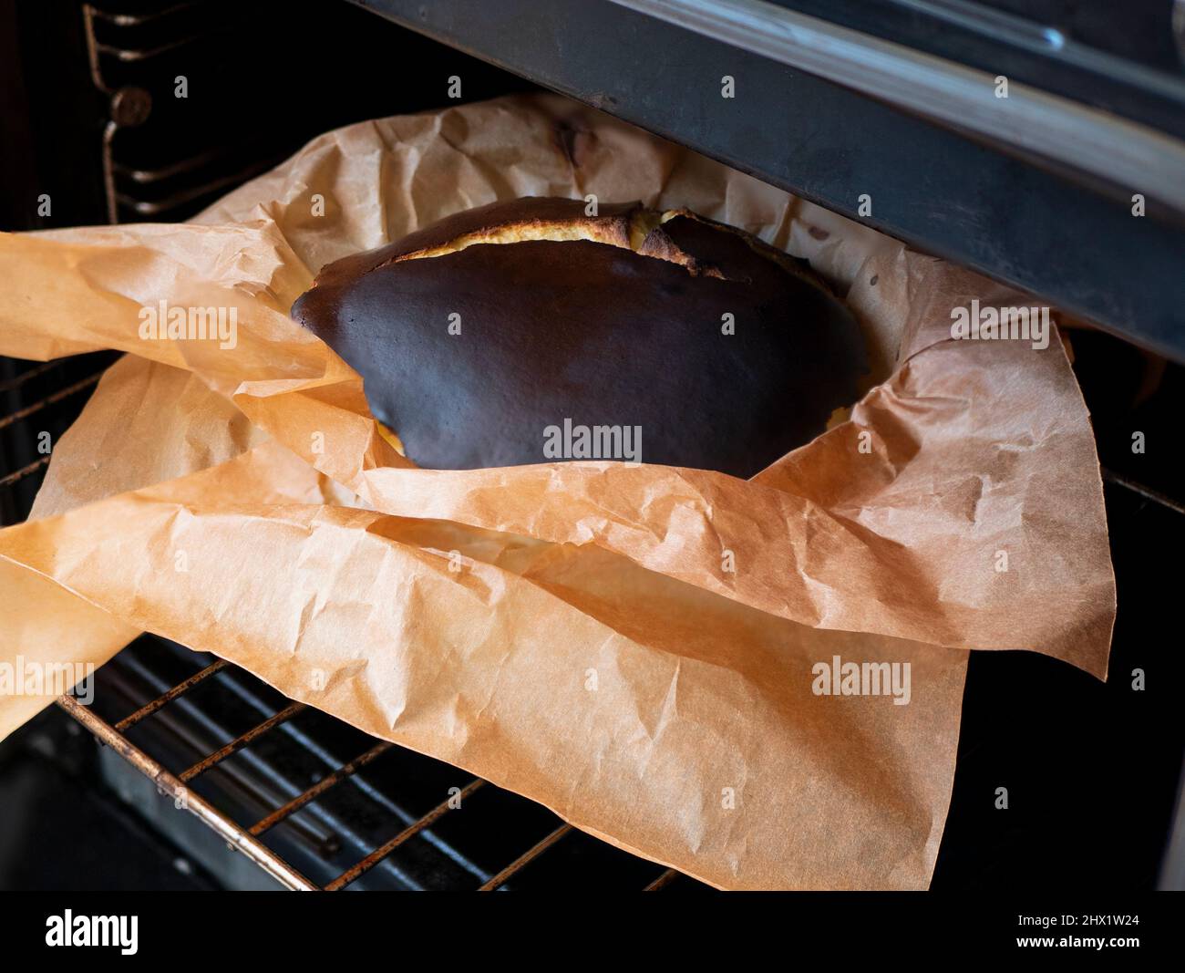 Sortir du four le cheesecake basque fraîchement cuit au four. Cuisson du gâteau rond caramélisé maison pendant le verrouillage Banque D'Images