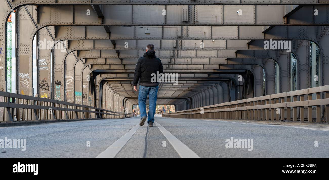 Homme marchant seul sur un pont vide au-dessus de la rivière Elbe à Hambourg, Allemagne. Banque D'Images