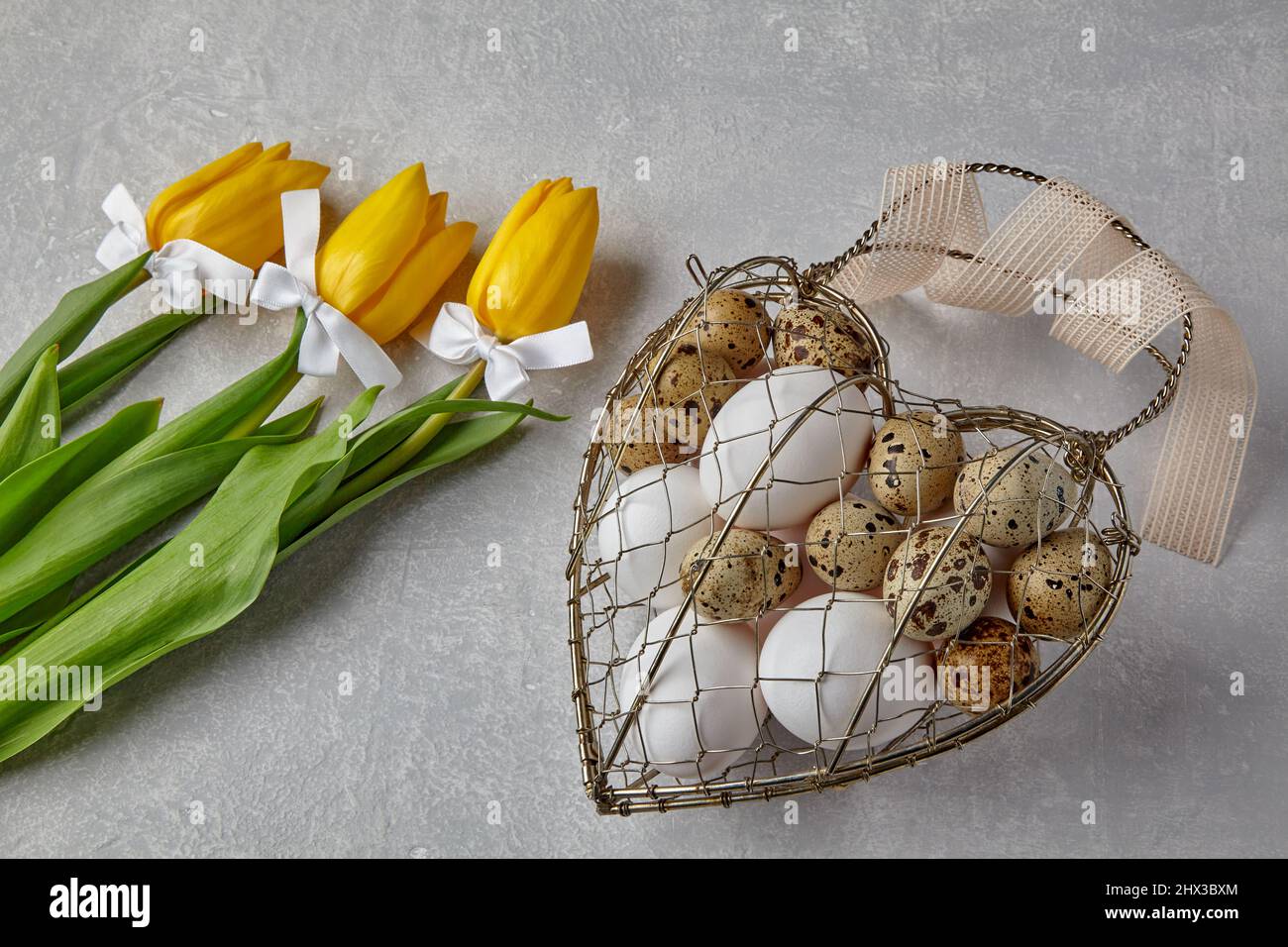 Œufs de poulet et de caille dans une boîte en fil métallique tissé en forme de coeur attachée Banque D'Images