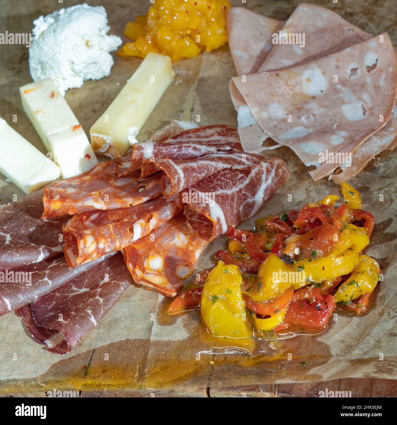 délicieux assortiment d'antipasti de viandes et de fromages avec poivrons rôtis sur un panneau en bois au format carré sélectif Banque D'Images