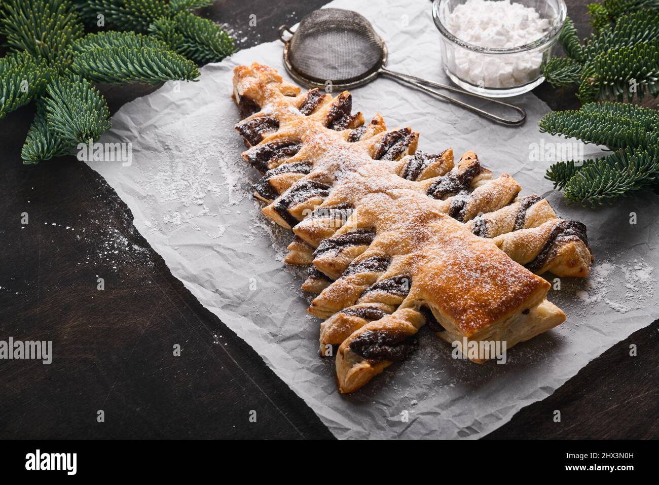 Pâte feuilletée arbre de Noël à la pâte de chocolat, saupoudrée de sucre sur fond de bois foncé.Pâtisseries de Noël ou de Noël.Vue de dessus.Co Banque D'Images