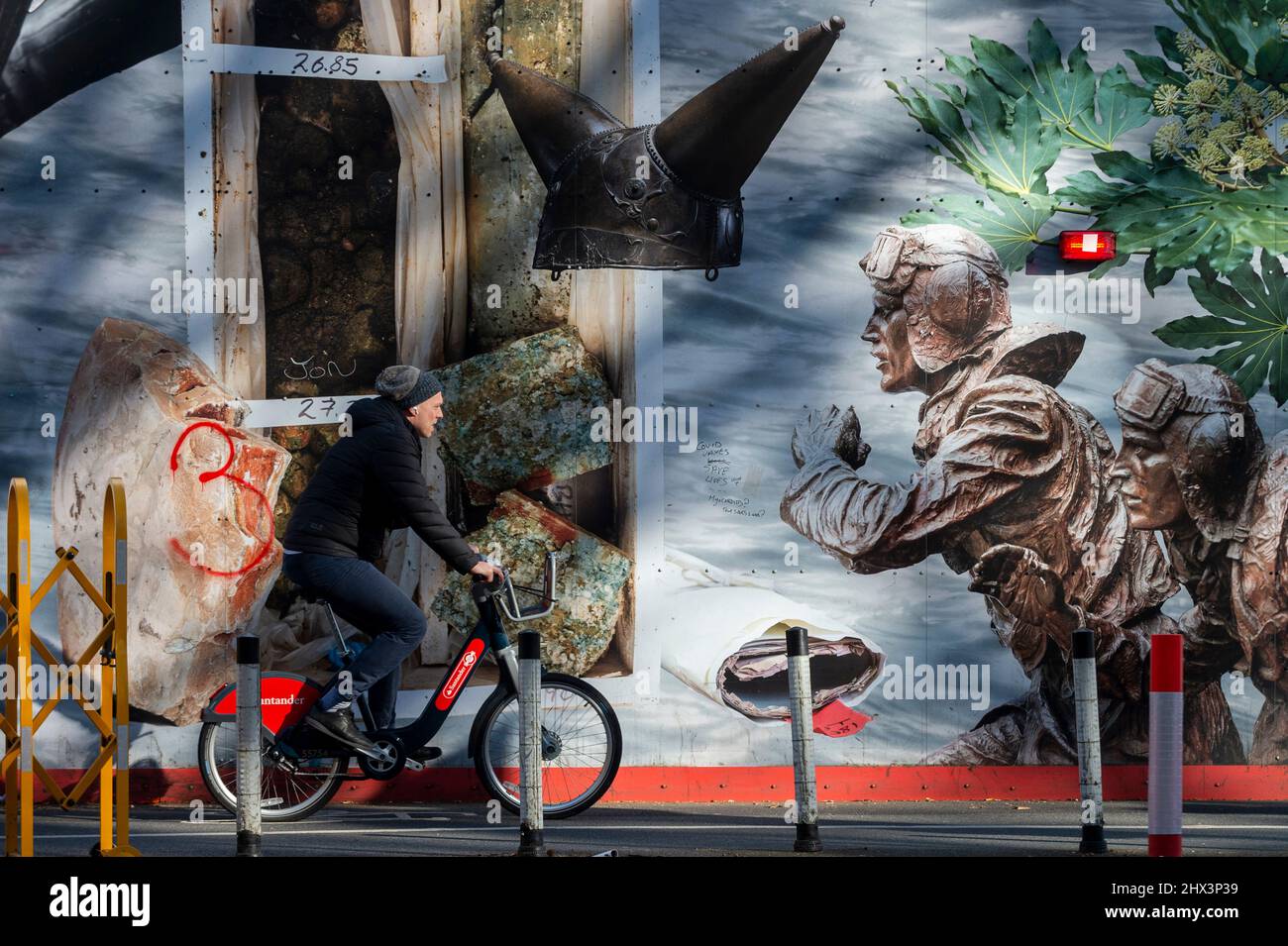 Londres, Royaume-Uni. 9 mars 2022. Un cycliste passe devant l’une des deux longues œuvres d’art de 25m comprenant « The Thames Wunderkammer: Tales from Victoria Embankment in Two Parts », de Simon Roberts commandé par Tideway. Les travaux sont inspirés par les monuments et les événements historiques et se déroulent sur la palissade de Victoria Embankment, derrière laquelle Tideway livrera le Thames Tideway tunnel, un tunnel d'égout de 25km dont l'urgence est nécessaire pour lutter contre la pollution des eaux usées dans la rivière Thames. Credit: Stephen Chung / Alamy Live News Banque D'Images