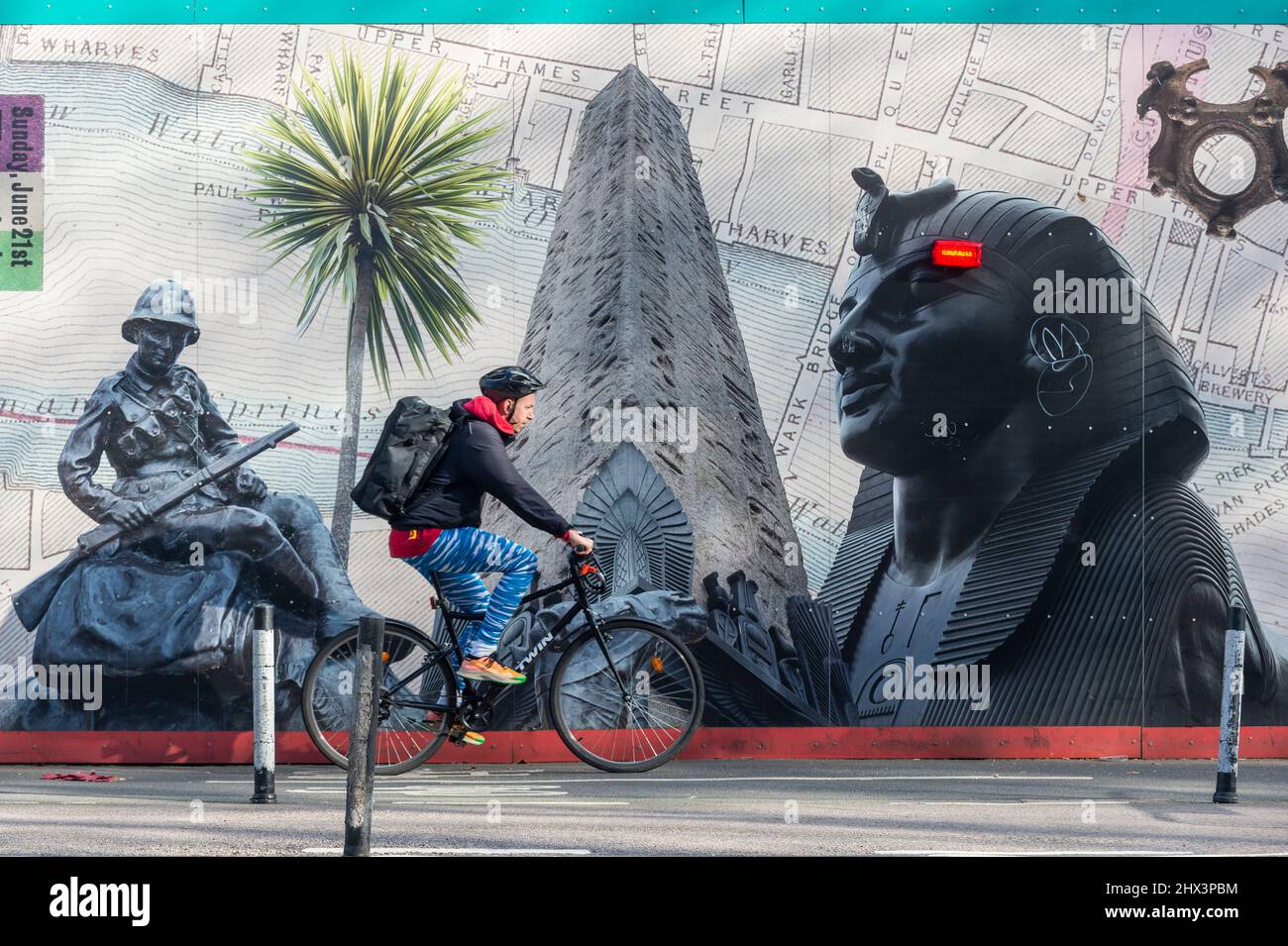 Londres, Royaume-Uni. 9 mars 2022. Un cycliste passe devant l’une des deux longues œuvres d’art de 25m comprenant « The Thames Wunderkammer: Tales from Victoria Embankment in Two Parts », de Simon Roberts commandé par Tideway. Les travaux sont inspirés par les monuments et les événements historiques et se déroulent sur la palissade de Victoria Embankment, derrière laquelle Tideway livrera le Thames Tideway tunnel, un tunnel d'égout de 25km dont l'urgence est nécessaire pour lutter contre la pollution des eaux usées dans la rivière Thames. Credit: Stephen Chung / Alamy Live News Banque D'Images