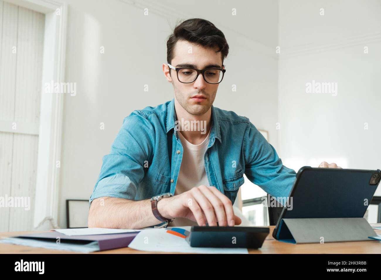 Un jeune homme gère ses finances depuis son domicile. Économiste travaille chez lui, indépendant Banque D'Images