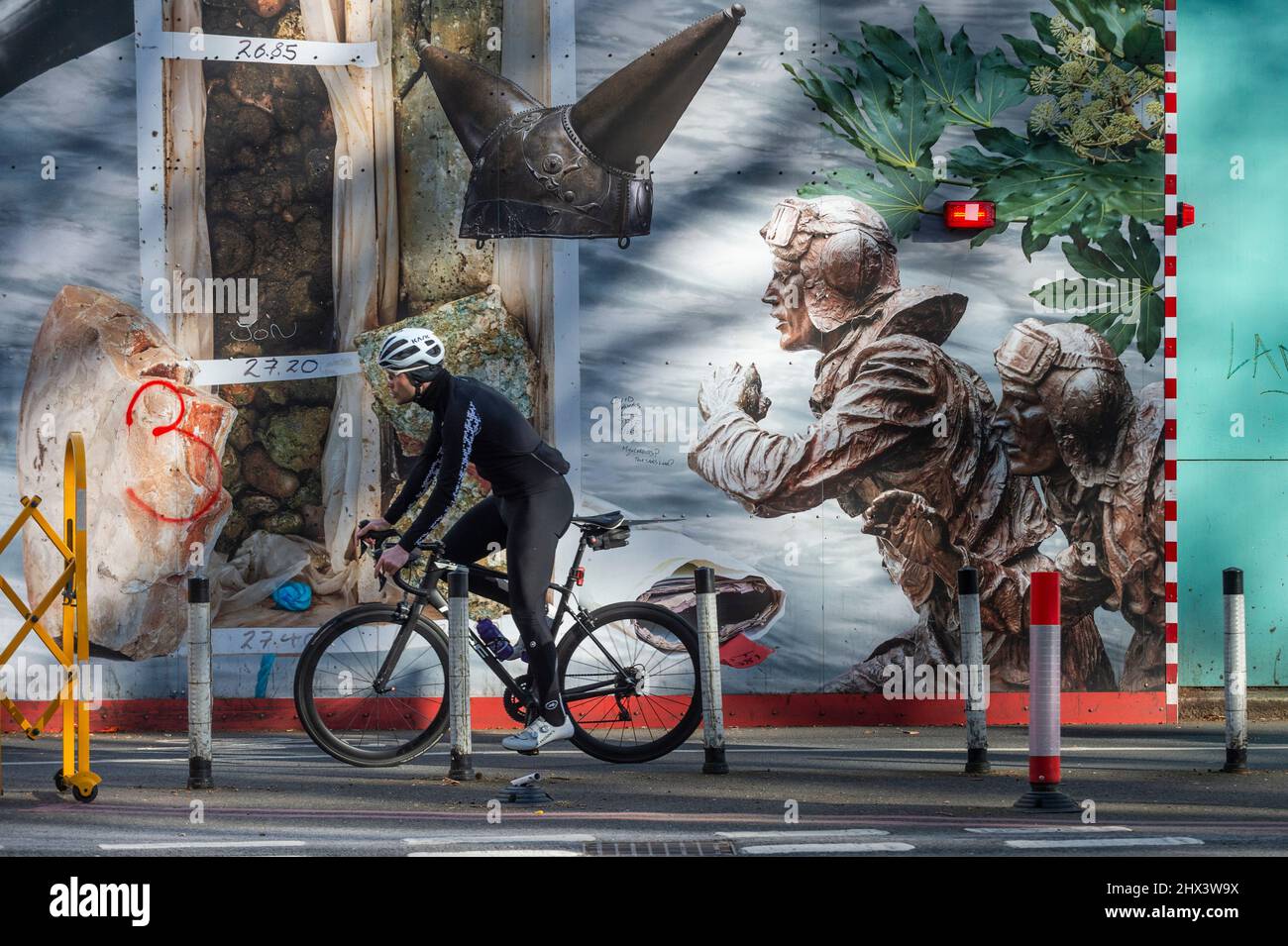 Londres, Royaume-Uni. 9 mars 2022. Un cycliste passe devant l’une des deux longues œuvres d’art de 25m comprenant « The Thames Wunderkammer: Tales from Victoria Embankment in Two Parts », de Simon Roberts commandé par Tideway. Les travaux sont inspirés par les monuments et les événements historiques et se déroulent sur la palissade de Victoria Embankment, derrière laquelle Tideway livrera le Thames Tideway tunnel, un tunnel d'égout de 25km dont l'urgence est nécessaire pour lutter contre la pollution des eaux usées dans la rivière Thames. Credit: Stephen Chung / Alamy Live News Banque D'Images