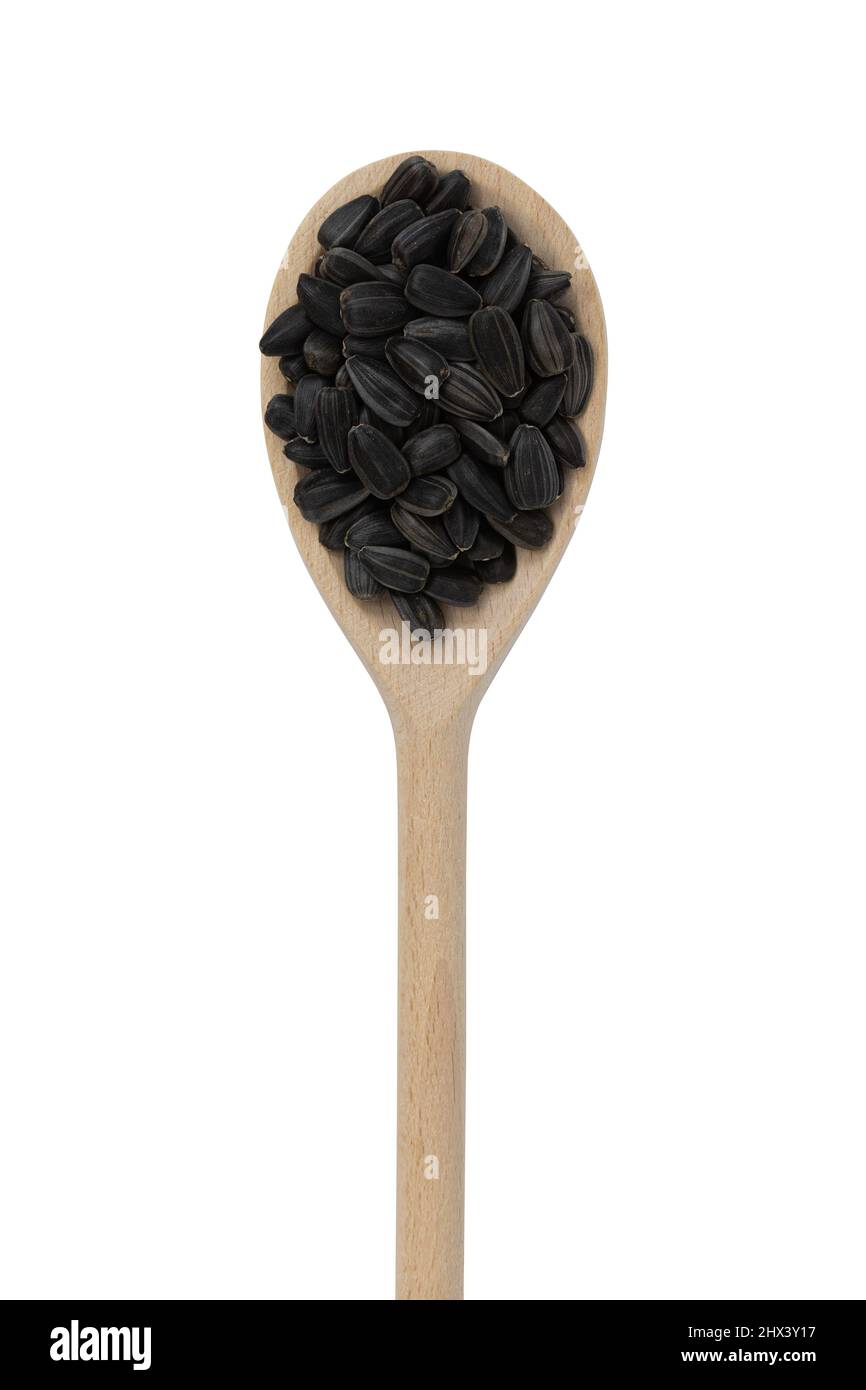graines de tournesol noires en cuillère en bois isolée sur fond blanc, vue de dessus, graines torréfiées non pelées Banque D'Images