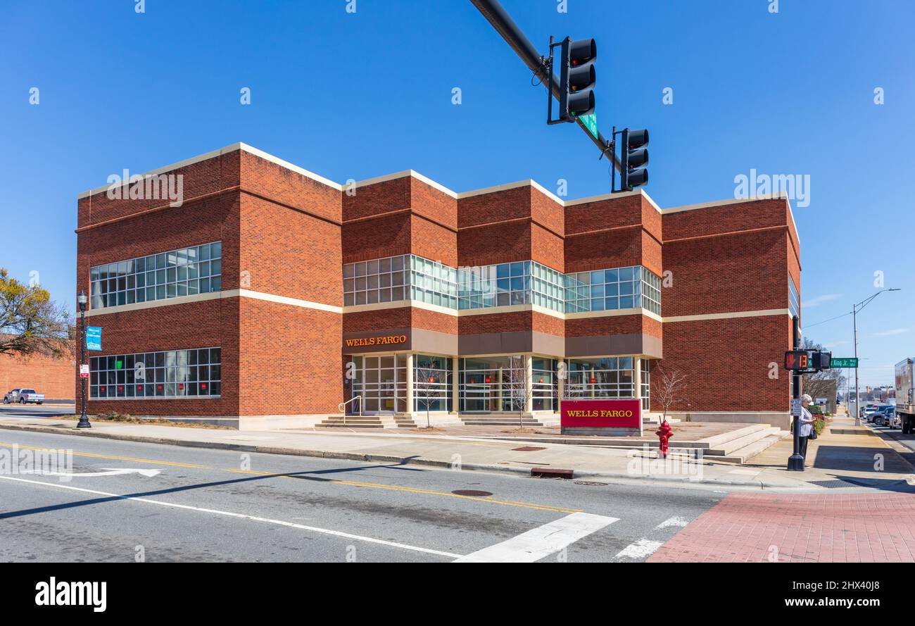 GASTONIA, NC, USA-3 MARS 2022: Vue de face de la banque Wells Fargo et des panneaux, y compris le panneau de rue. Une femme au coin de la rue. Banque D'Images