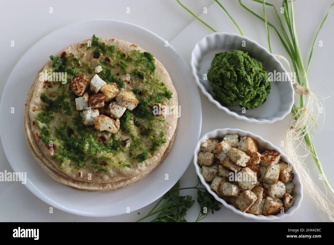 Pain plat indien étalé de condiment à l'ail vert et servi avec du fromage cottage sauté. Prise de vue sur fond blanc. Banque D'Images