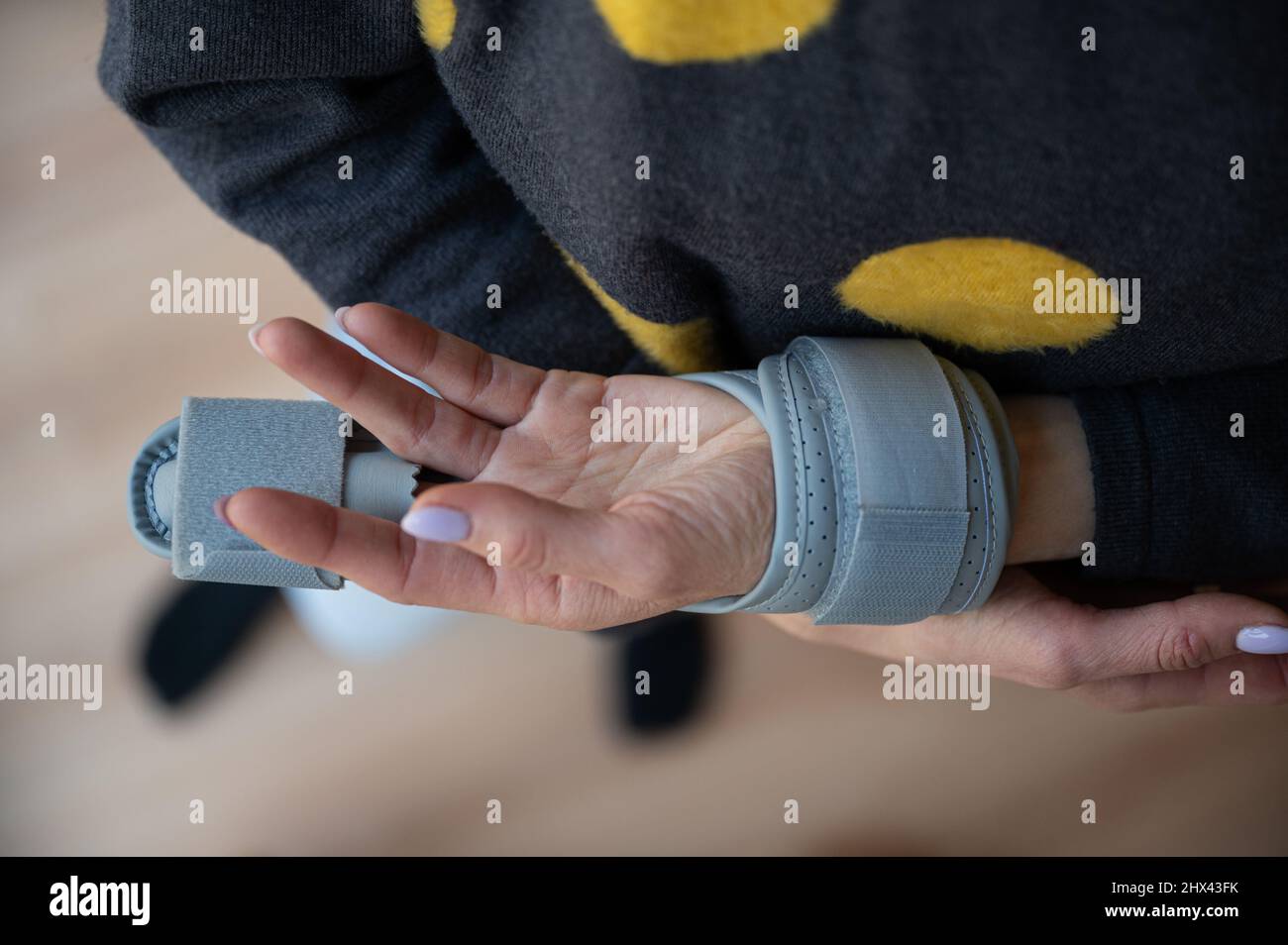 Vue de dessus d'une femme portant un corset sur son doigt cassé tenant et nourrissant sa main blessée dans l'autre bras. Banque D'Images