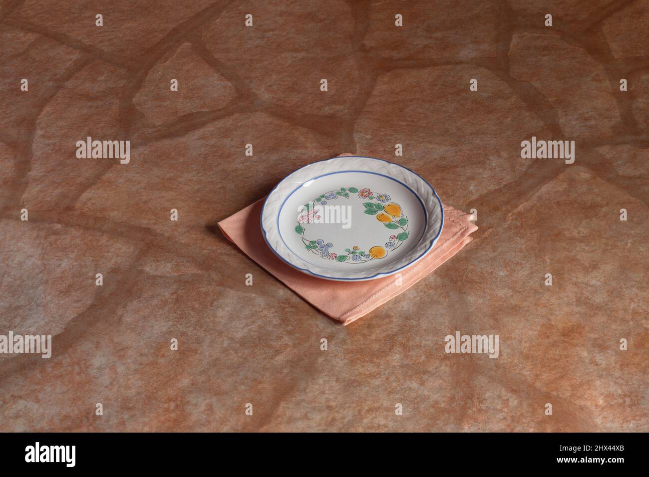 Assiette classique décorée à la main avec des motifs floraux, des raisins et des citrons avec une bordure bleue sur une élégante serviette en tissu sur une table rustique en pierre. Nourriture et p Banque D'Images