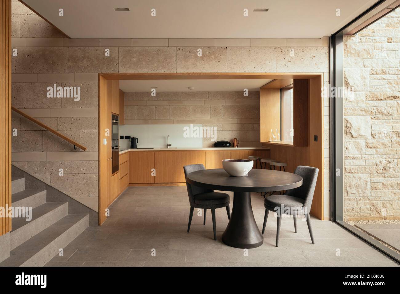 Intérieur d'un espace de séjour ouvert comprenant une salle à manger, un escalier et une cuisine, avec des murs en pierre polie et rugueuse. Clifftops, Dorset Banque D'Images