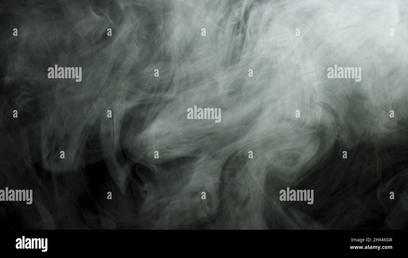 Gros plan pour une fumée blanche épaisse qui se propage sur fond noir. Brouillard dense volant isolé dans l'obscurité. Banque D'Images