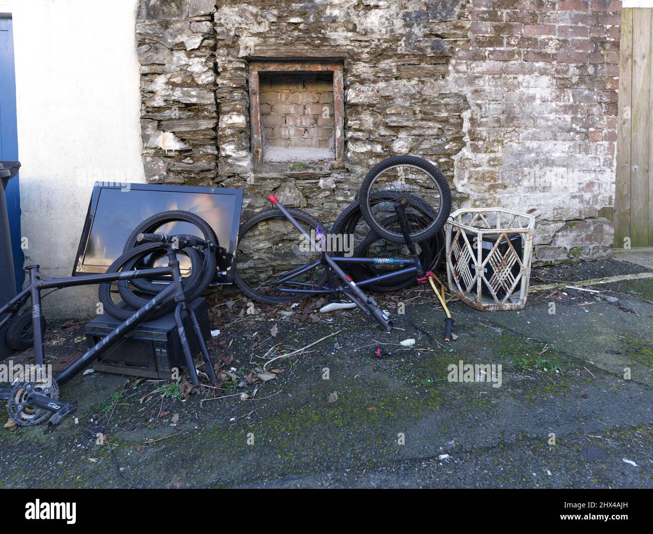 Des déchets électriques et de cylces ont quitté l'arrière d'une maison dans une allée. Banque D'Images