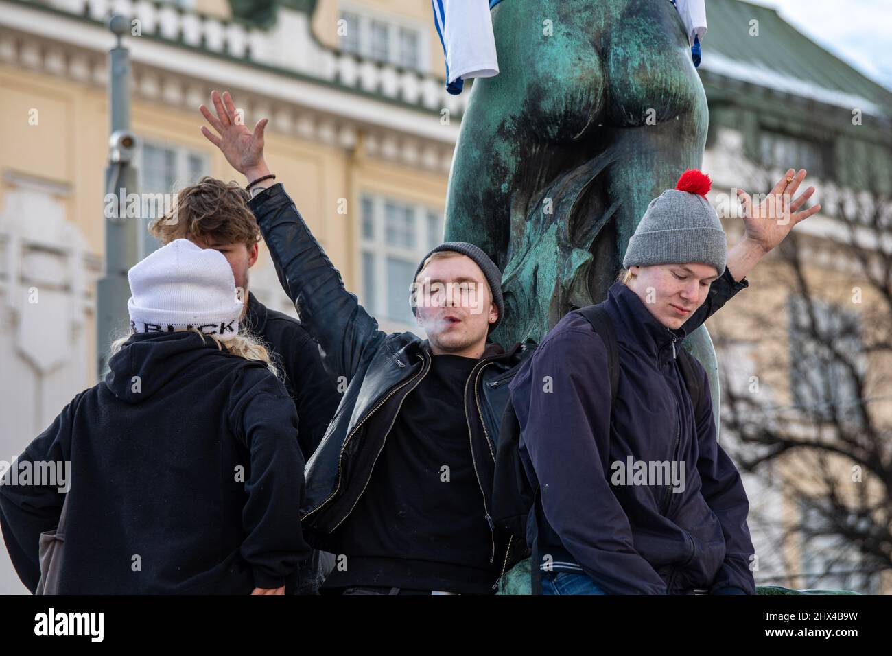 Des jeunes célèbrent la médaille d'or du hockey sur glace olympique masculin sur la sculpture Havis Amanda à Helsinki, en Finlande Banque D'Images