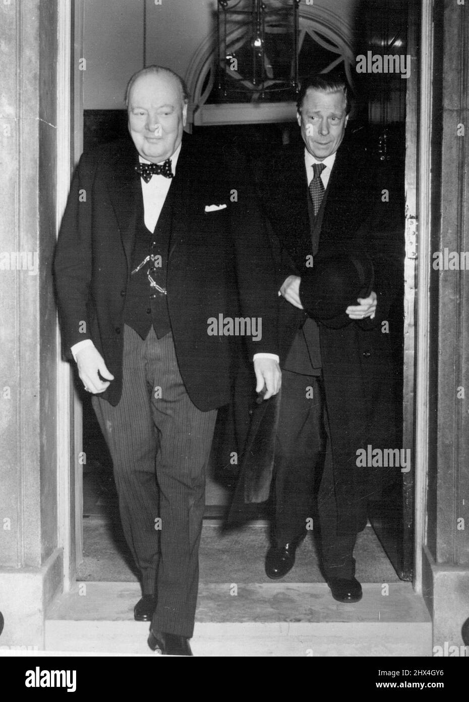 Le visiteur du temps du thé Un sourire M. Churchill mène à la porte de la rue Downing no 10. Le duc de Windsor, chaudement recouvert d'un chapeau à la main, suit. C'est ainsi que leur temps de thé a pris fin hier. Le duc a appelé M. Churchill de la maison Marlborough, où il séjourne avec la reine Mary. Demain, il déjeuner avec la Reine. 19 novembre 1952. (Photo par photo de contrat de courrier quotidien) Banque D'Images