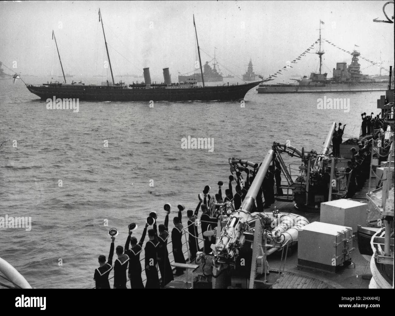 H.M. le roi examine sa flotte. H.M. le Roi a passé en revue la flotte de la Grande-Bretagne, entourée de navires de guerre de toutes les parties du monde? Hors tête d'impression. Trois Cheers de H.M.S. Londres comme les hommes ont tenu le navire et H.M. le roi a inspecté la flotte du Royal Yacht 'Victoria et Albert'. La reine Elizabeth est vue en arrière-plan. Mai 20 1937. (Photo de Sport & General Press Agency Limited). Banque D'Images