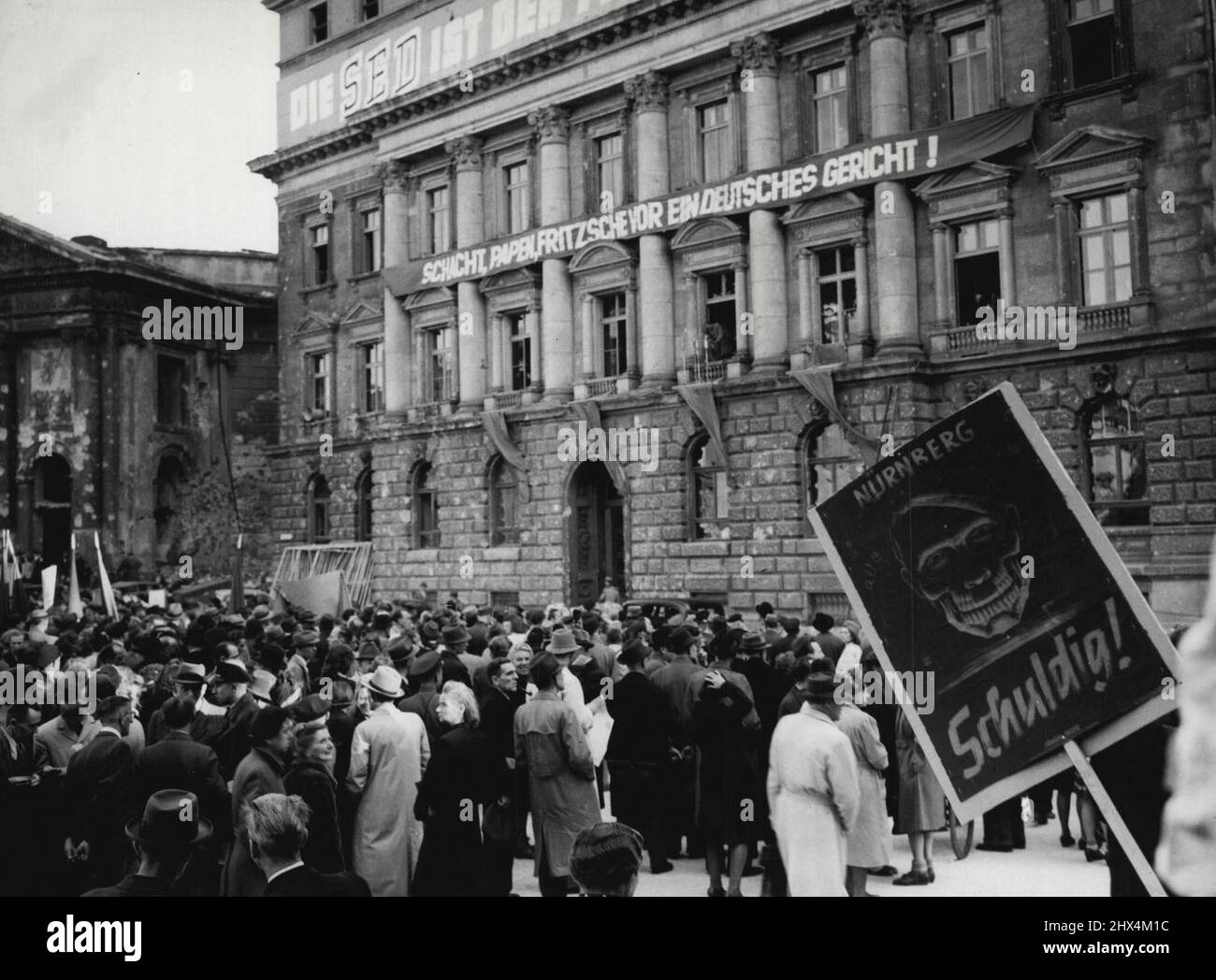 Les Allemands manifestent contre les acquittements de Nuremberg -- Une vue générale des manifestants sur la place Oper. En arrière-plan se trouve le siège de SED, anciennement la Dresden Bank et les chefs de bannière: 'Papen Schacht et Fritsche pour un procès devant la Cour allemande.' L'écriteau du crâne au premier plan indique que tous sont coupables. Cinquante mille Allemands se sont rassemblés dans le secteur russe de Berlin le 2 octobre lors d'une manifestation du parti d'unité sociale pour protester contre les acquittements du Tridunal de Nuremberg, les bannières qu'ils ont transportées ont appelé à la mort de tous les criminels nazis de Nuremberg. 22 octobre 1946. (Photo par photo de presse associée). Banque D'Images
