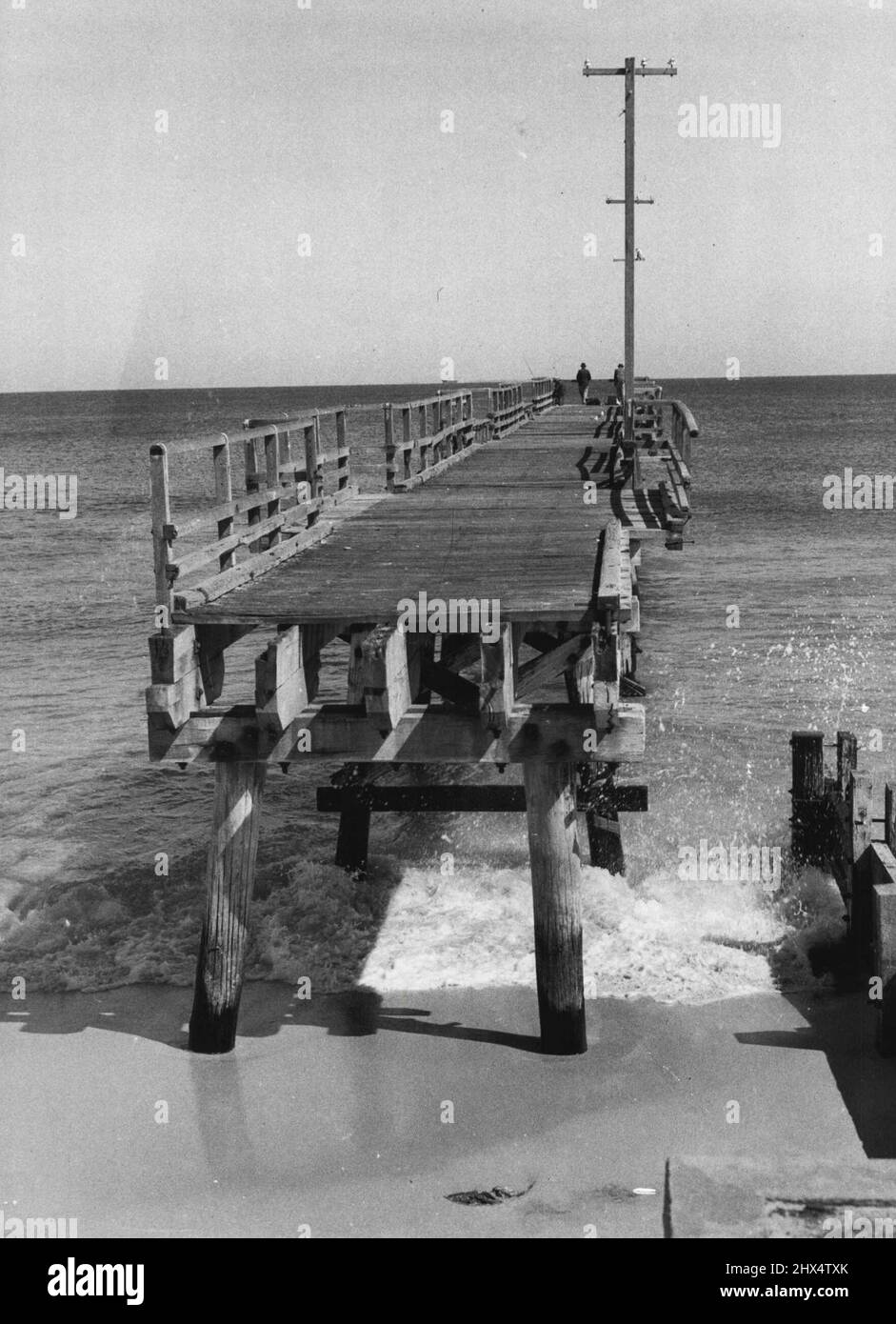 Lorsque le Conseil municipal de Perth a commencé à retirer l'ancienne jetée de Cotteslce parce qu'elle était dangereuse, les pêcheurs réguliers n'ont pas été dissuadés. Ils ont simplement pris une échelle dans le surf, ont grimpé sur les restes de la jetée et ont pêché au contenu de leur coeur. 05 mai 1952. Banque D'Images