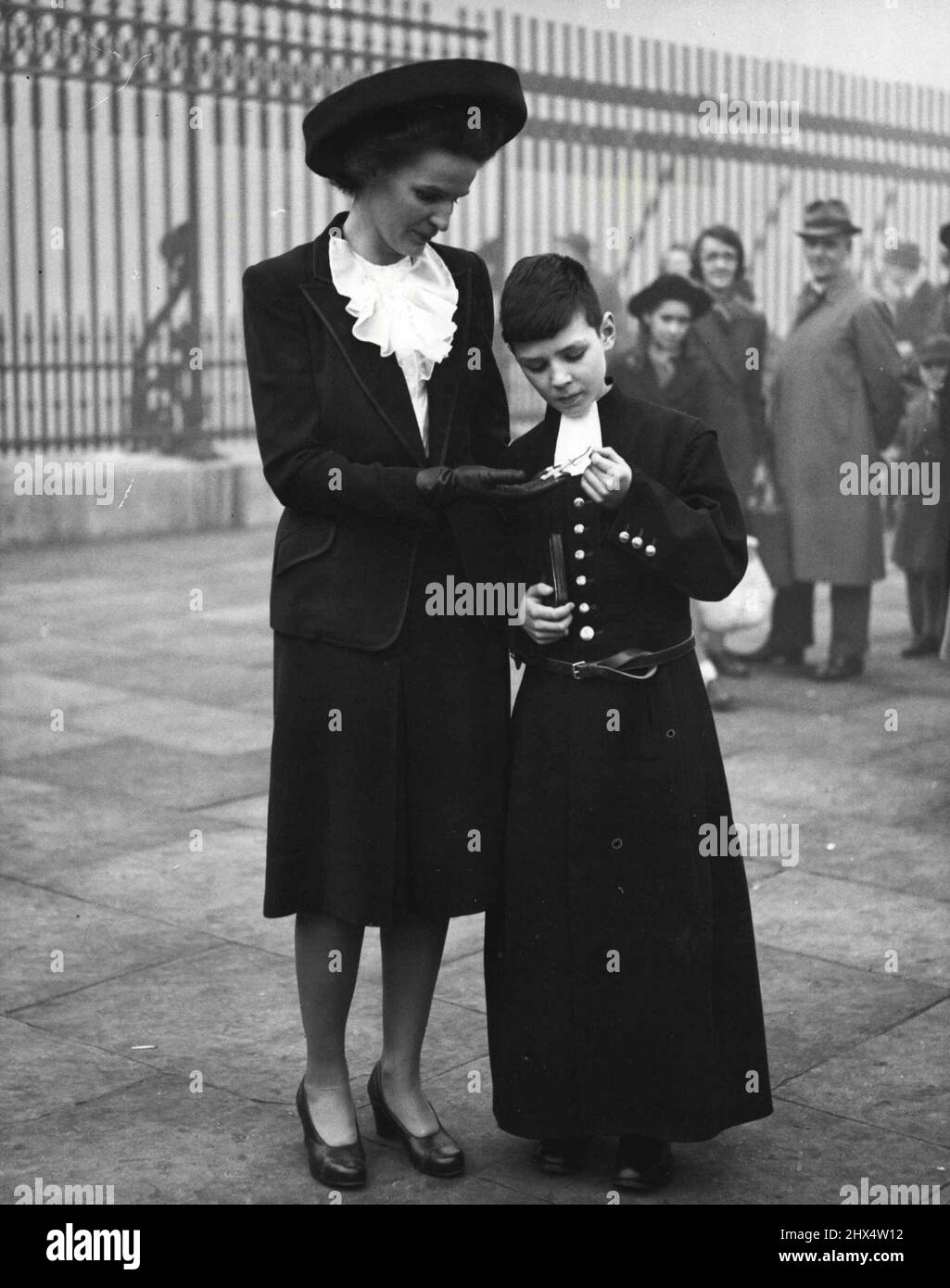 Investiture du prochain-de-Kin -- Mme D. J. C. Britton, de Fordingbridge, Hants, et son fils Peter, de l'École de l'Hôpital du Christ, regardant la Croix militaire de son défunt mari. Le major D. J. C. Britton a reçu le M. C. pour bravoure en extrême-Orient lorsqu'il a servi avec la Force 136; il est tombé par parachute derrière les lignes ennemies. Sa Majesté le Roi a tenu une investiture au Palais de Buckingham ce matin, mardi, lorsqu'il a remis des prix aux proches parents d'officiers et d'autres grades. 5 novembre 1946. Banque D'Images
