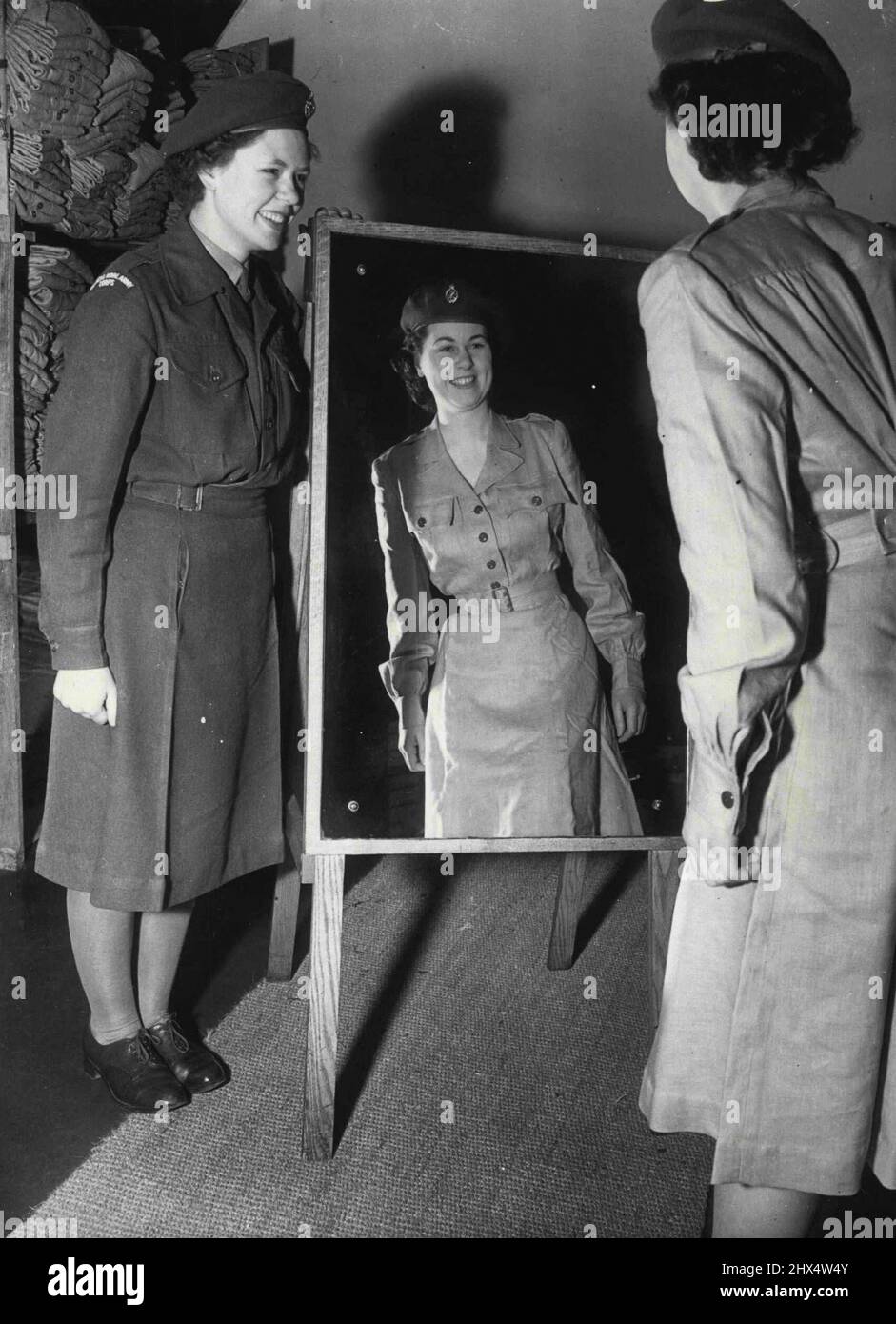 Satisfait de sa réflexion - dans la nouvelle robe tropicale, vient de paraître pour l'extrême-Orient seulement, Irene Evans, 21 ans, admire son look tandis que Doreen Brown tient le miroir pour elle. Le nouveau « problème » est une robe en lin d'une seule pièce. La photo a été prise au jour le jour au dépôt féminin du corps royal de l'armée, à Guildford, dans le Surrey, d'où les filles ont quitté plus tard pour Southampton. Ils embarqueront pour morrow dans l'Empire Windrush pour l'extrême-Orient. 16 janvier 1952. (Photo de Paul Popper, Paul Popper Ltd.). Banque D'Images