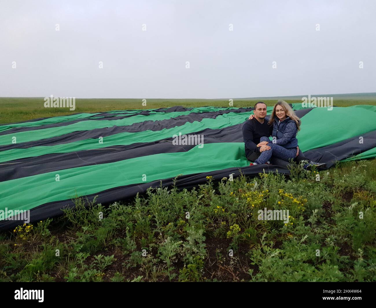 Couple aventure amour sur l'air chaud ballon pastèque. L'homme et la femme embrassent le hug l'un l'autre. Brûleur dirigeant la flamme dans l'enveloppe. Envolez-vous dans le ciel bleu du matin. Les gens heureux prennent le selfie dans le ballon d'air chaud. Banque D'Images