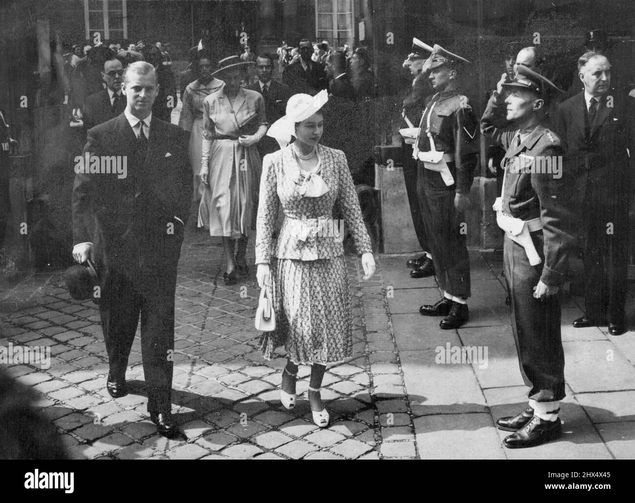 La princesse marche jusqu'à l'église de Paris -- la princesse Elizabeth, dans un costume vert et blanc imprimé de deux pièces avec jupe plissée, chapeau de paille blanc, chaussures blanches, gant et sac, laissant l'église de l'ambassade britannique avec le duc d'Édimbourg après avoir assisté au service divin. Sir Oliver Harvey, ambassadeur britannique, et Lady Harvay se trouvent derrière vous. Presque tous les membres de la colonie britannique à Paris sont venus voir la princesse et le duc alors qu'ils marchaient de l'ambassade à l'église de la rue d'Agusseau, où l'aumônier, le Dr G. A. Chambers, prêchait le sermon. 17 mai 1948. Banque D'Images