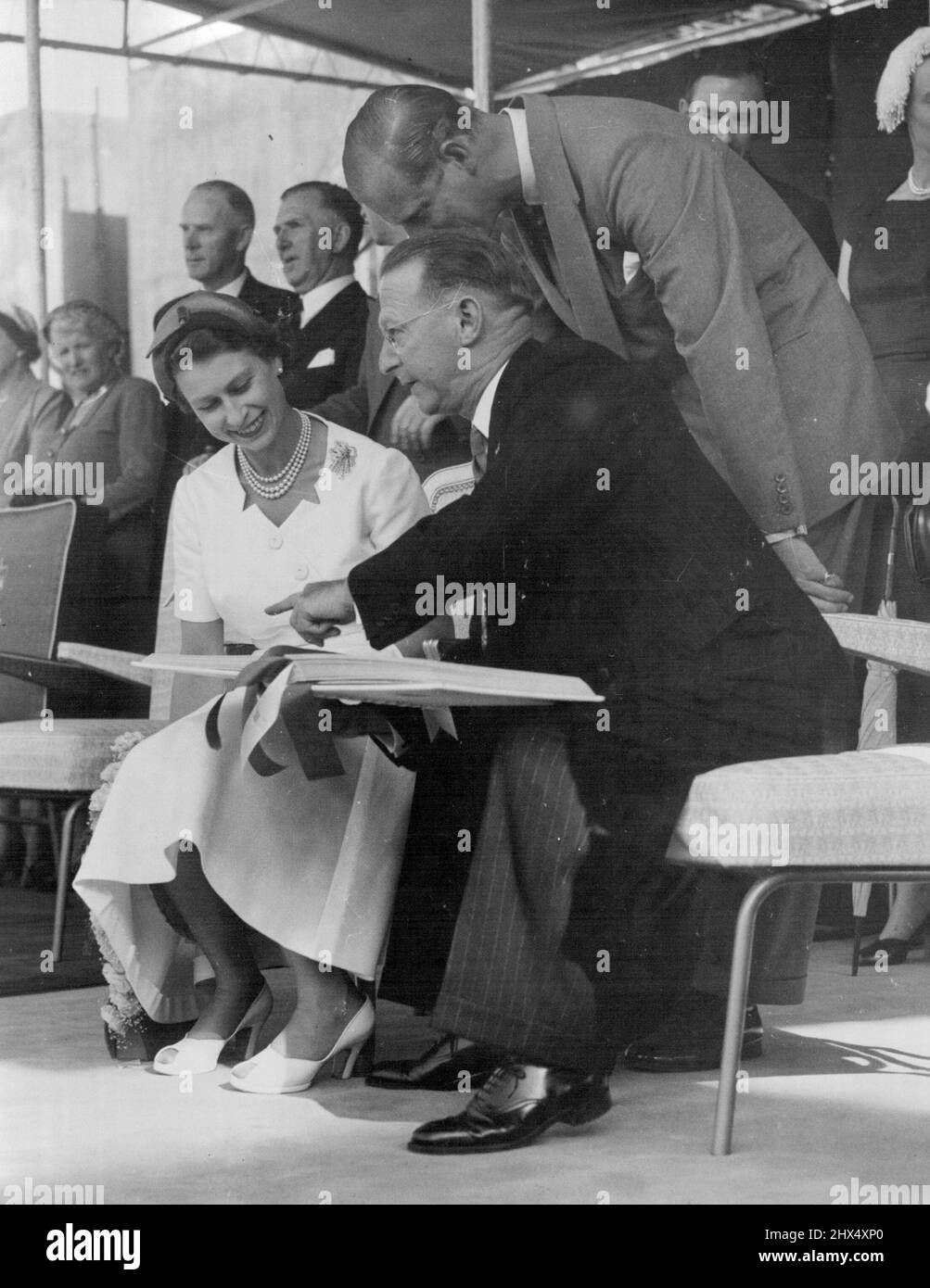 La reine Elizabeth signe un livre à son arrivée à Startford. Avec sa Majesté, M. N. H. Moss, maire de Stratford. 14 janvier 1954. Banque D'Images