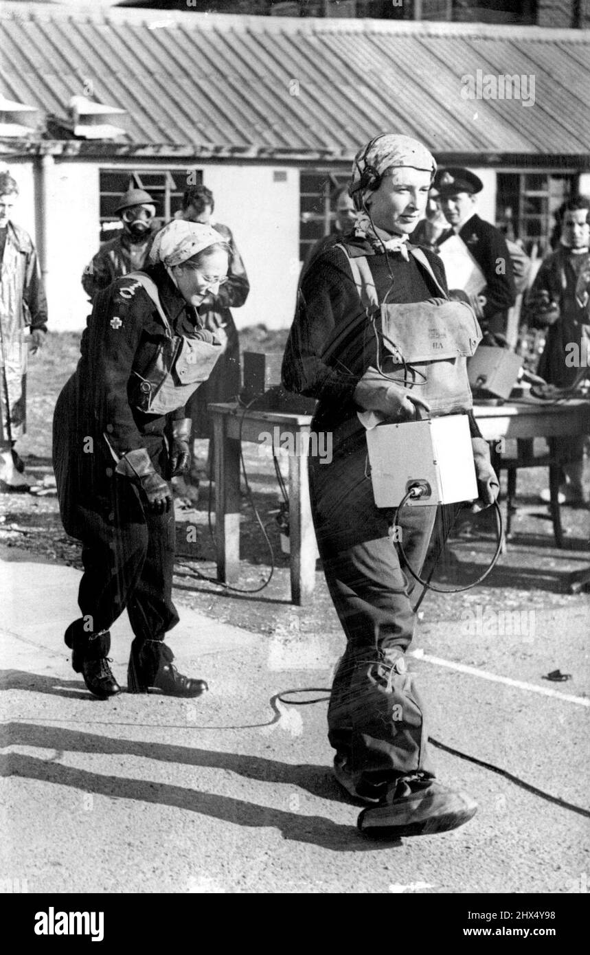 Mlle PAM Weston, des services bénévoles de Womens, portant un compteur Geiger, et suivie de Mlle May Morris, de la Croix-Rouge britannique, sort d'une zone radio-active présumée. L'instrument donne une série de clics quand la radio-activité est rencontrée et permet ainsi à la partie de sauvetage de trouver leur chemin à travers la zone infectée.Une démonstration a été donnée à Winchester, Hampshire, par un groupe d'experts de H.M.S. « Phoenix » présentant les différents dispositifs de sécurité conçus pour protéger le public et les membres de la Défense civile dans des conditions où la radioactivité est susceptible d'être présente. Fév Banque D'Images