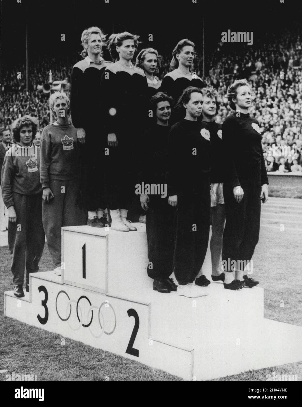 Jeux Olympiques - Blankers-Koen remporte la quatrième médaille olympique - et Relais pour la Hollande : Mme Fanny Blankers-Koen et les membres de l'équipe hollandaise gagnante, ainsi que les gagnants suivants, attirent l'attention sur la tribune de la victoire au stade de Wembley, les hymnes nationaux rendant hommage à leur triomphe dans le relais féminin de 400 mètres. En remportant le relais pour la Hollande, Mme Blankers-Koen a remporté sa quatrième victoire aux Jeux olympiques de 1948. Les Australiens sont au deuxième rang de la course, les Canadiennes sont au troisième rang. 06 août 1948. (Photo de l'Association olympique de photo). Banque D'Images