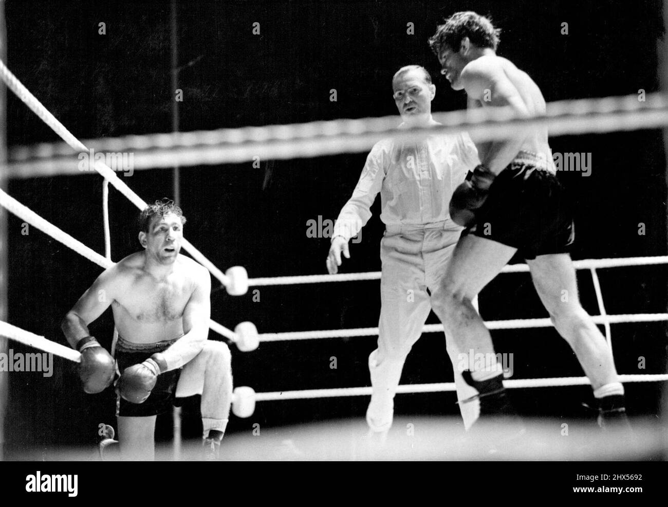 Freddie Miles bat Gus Lesnevitch pour gagner le titre mondial -- Lesnevitch, qui a été mal coupé dans le neuvième tour. Teddy Waltham, l'arbitre vu au centre. Freddie Mills (Gt. Britain) a battu Gus Lesnevitch (É.-U.) dans leur concours pour le championnat du monde de poids lourds légers, à la ville blanche, Londres. Mille a gagné sur les points. 27 juin 1948. Banque D'Images