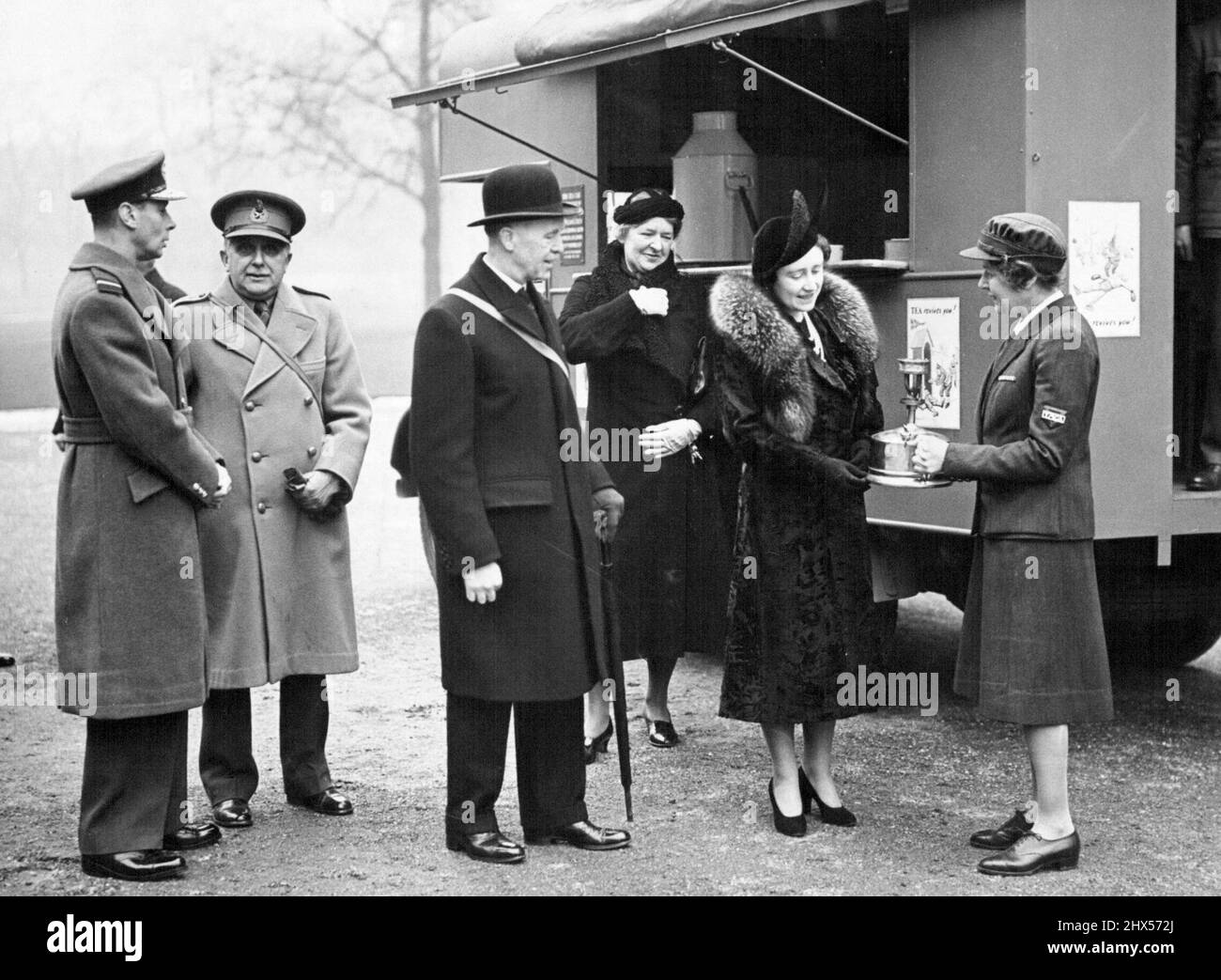 Le roi et la reine inspecte la voiture de thé mobile - la reine étant montrée une partie de l'équipement de la voiture de thé mobile par Lady Blane (en uniforme Y.M.C.A.) tandis que le roi (à gauche) discute avec le major-général Sir John Brown. Le roi et la reine ont inspecté aujourd'hui (vendredi) une unité de voiture de thé mobile Y.M.C.A. pour les troupes dans le domaine de Buckingham Palace avant son départ pour la France. La voiture de thé inspectée par leurs Majestés a été levée par vente aux enchères par le maire de Londres, au Tea Exchange. 11 mars 1940. (Photo de London News Agency photos Ltd.). Banque D'Images