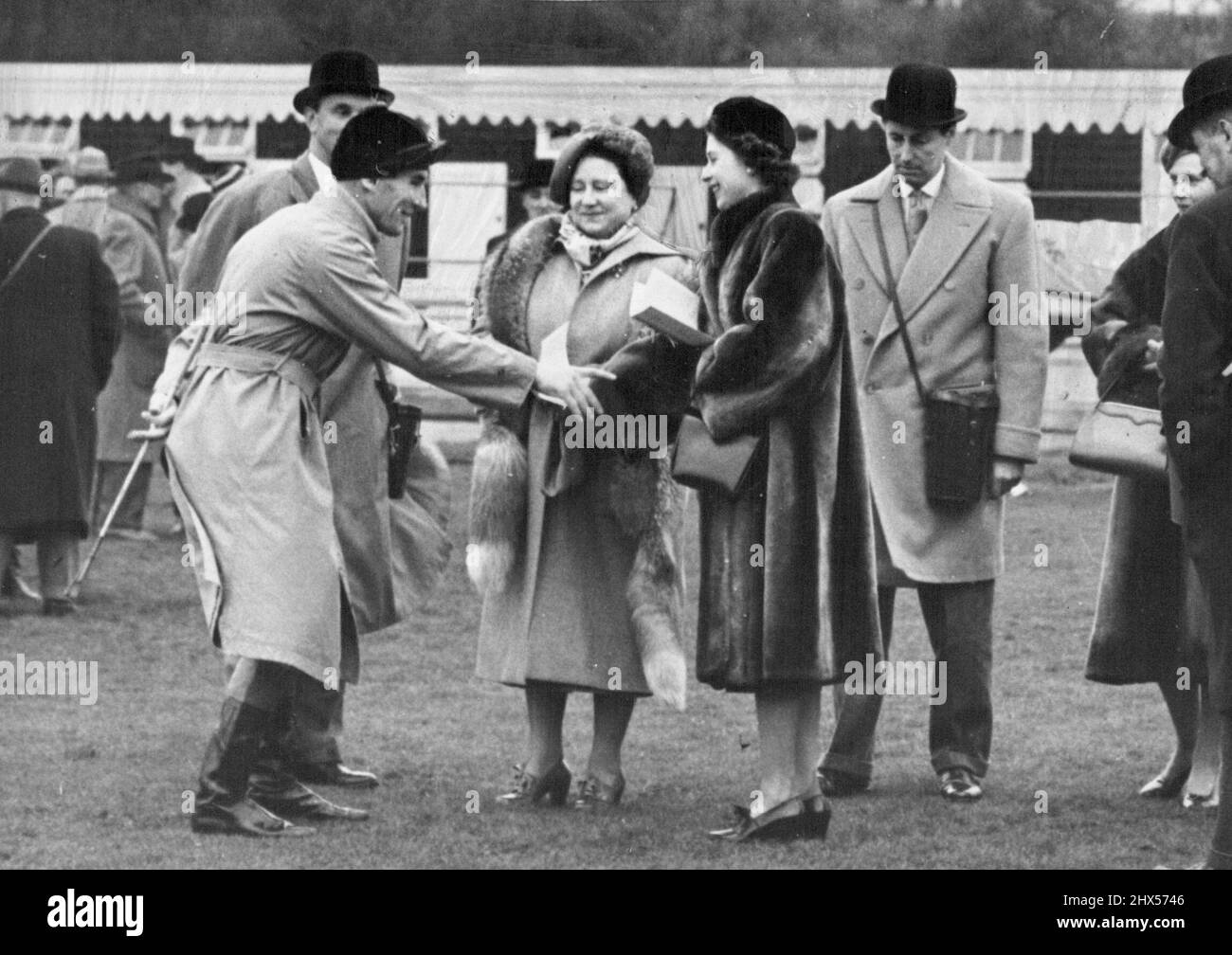 La reine Elizabeth et la princesse Elizabeth, qui se sont rendus à Hurst Park pour voir le cheval de la reine Devon loch courir, sont amusés par la description graphique de la course du jockey Brian Marshall. Le Loch Devon a pris la deuxième place. 26 janvier 1952. Banque D'Images