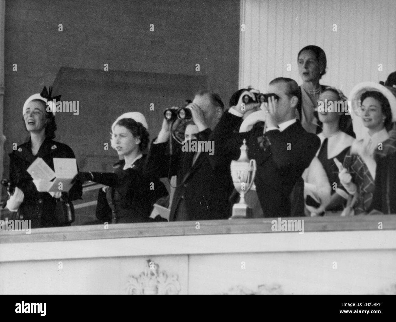 Jumelles dans la Royal Box -- comme la Reine pointe (deuxième à partir de la gauche), les Ducs de Gloucester (centre) et d'Édimbourg suivent la course avec des jumelles de la Royal Box à Ascot, Berkshire, cet après-midi, le 18 juin, le deuxième jour de la rencontre de Royal Ascot. Les autres éléments de la boîte ne sont pas identifiés. La Reine est vêtue de noir et porte un chapeau blanc. 17 juin 1952. (Photo par BIPPA). Banque D'Images