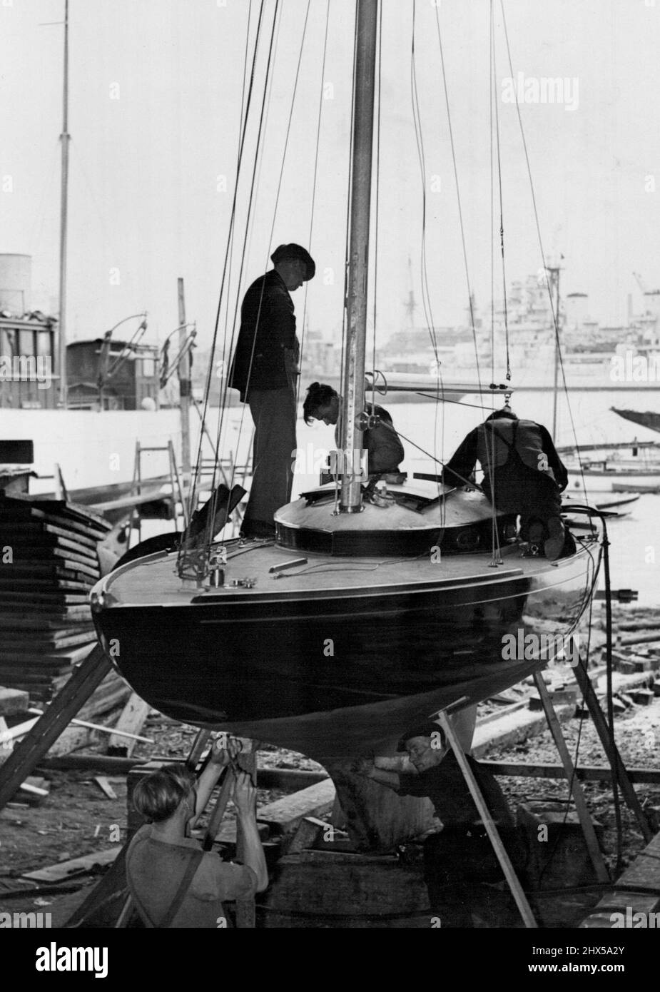 Nouveau Royal Racing Yacht nears achèvement -- les ouvriers préparant le Bluebottle pour ses essais, dans les chantiers de construction navale de Gosport. Un nouveau yacht royal de course de la classe Dragon, un cadeau de mariage à la princesse Elizabeth et au duc d'Édimbourg du Island Sailing Club (île de Wight) est en voie d'achèvement aux chantiers de Gosport, Hants, où elle est construite. Le yacht, qui est de plus de 29 pieds de long, a été nommé Bluebottle, et sera vu dans le Solent cette semaine pour l'étirement de voile. On espère que le navire sera présenté officiellement à leurs Altesses Royales à Cowes. 29 juin 1948. Banque D'Images