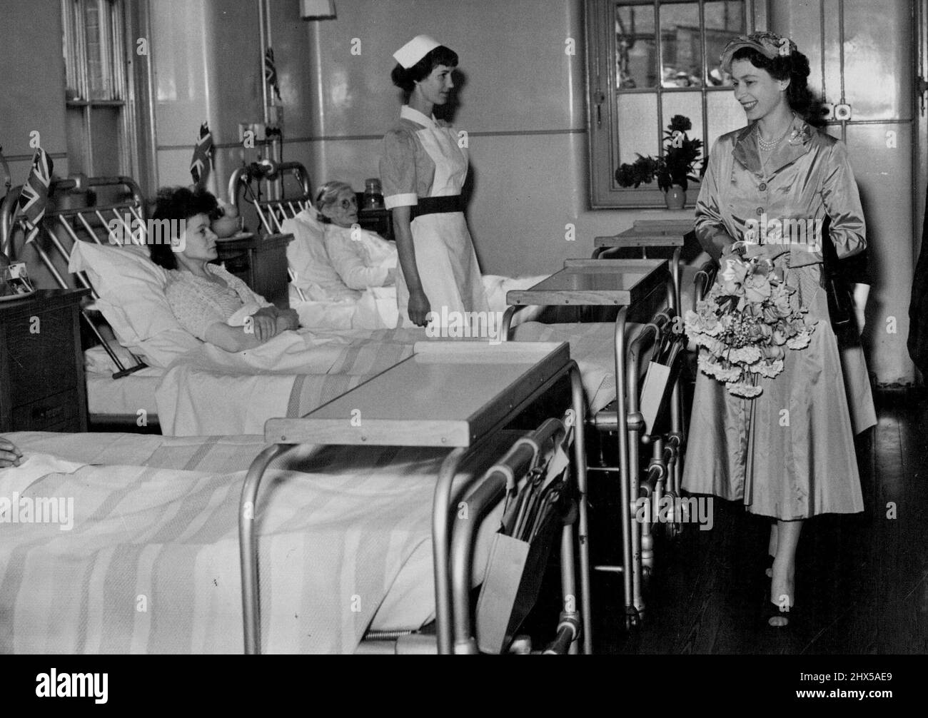 La Reine visite l'hôpital de Hammersmith -- les patients de l'hôpital de Hammersmith obtiennent un vrai 'tonique' tandis que la Reine souriante marche dans leur quartier. Les patients ont été assez bien emmenés au soleil pour regarder l'arrivée de la Reine et sa Majesté a visité les quartiers pour parler à ceux qui ne sont pas assez bien pour être pris à l'extérieur. H.M. la Reine a effectué cet après-midi une visite à l'hôpital Hammersmith, qui célèbre le 50th. Anniversaire de sa fondation, en conjonction avec le 20th. Anniversaire de l'inauguration de la faculté de médecine de troisième cycle de l'Université de Londres, qui se trouve au Banque D'Images