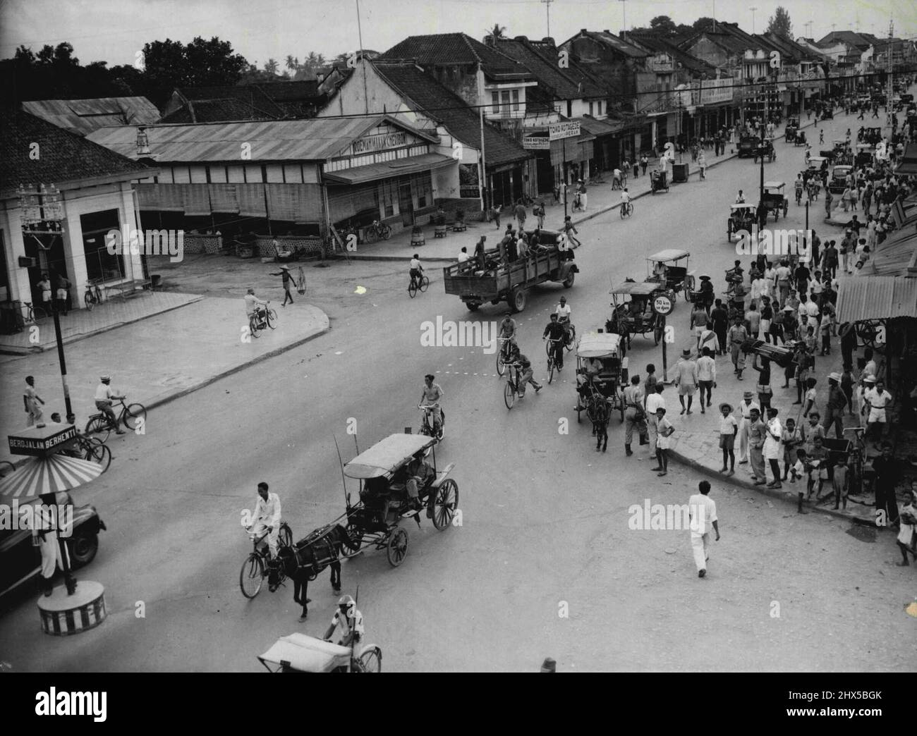 Jogjakarta - capitale républicaine de Java. Une vue générale de la scène dans la rue Malioboro, artère principale de Jogjakarta, Java. Malgré les difficultés en Indonésie, les affaires se poursuit comme d'habitude. Comme précaution contre l'« invasion », les moyens de transport publics sont « armés » de lances en bambou. Ces armes minces peuvent être vues sur des véhicules tirés par des chevaux dans cette image. Les habitants de la ville républicaine s'intéressent vivement à l'évolution des événements et des panneaux d'information sont affichés dans la rue. 22 août 1947. (Photo par photo de presse associée). Banque D'Images