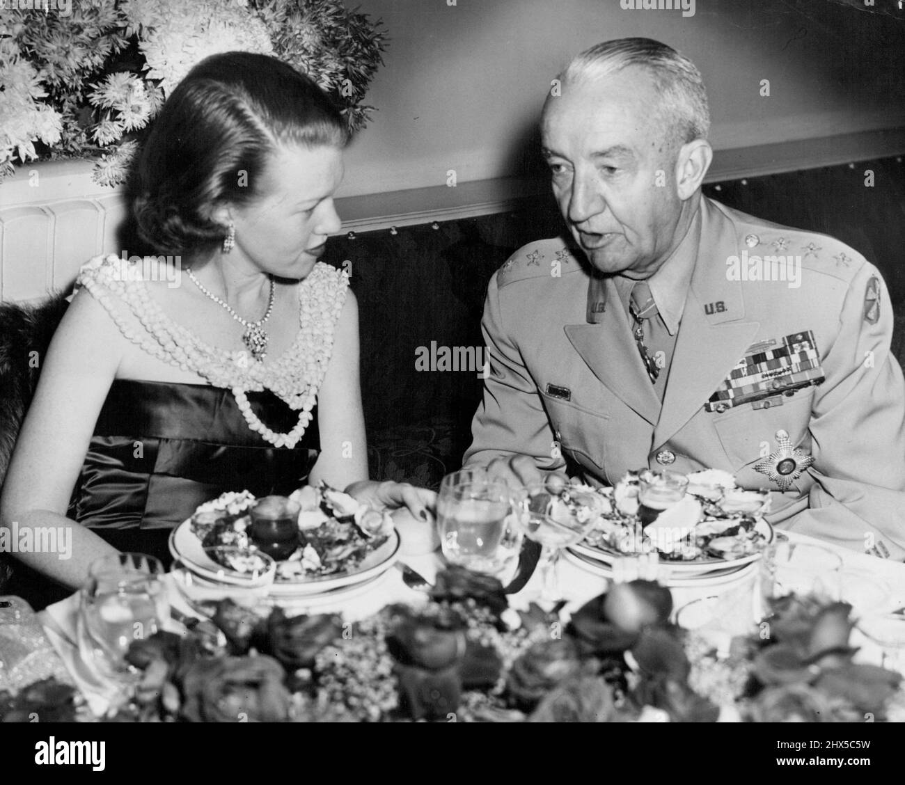 A la table officielle, le général Lieut Eichelberger et Mme Donald Smith, épouse du consul général des États-Unis, ont une discussion sérieuse. La robe de satin bleu minuit de Mme Smith a une drapery d'agitation. 19 mai 1952. Banque D'Images