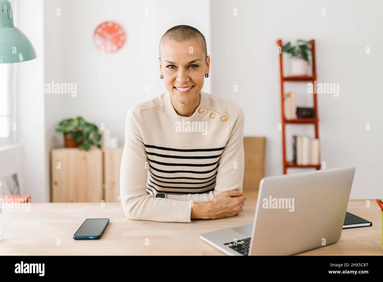 Portrait d'une femme rasée et attirante dans un bureau à domicile regardant un appareil photo Banque D'Images Portrait d'une femme rasée et attirante dans un bureau à domicile regardant un appareil photo Banque D'Images