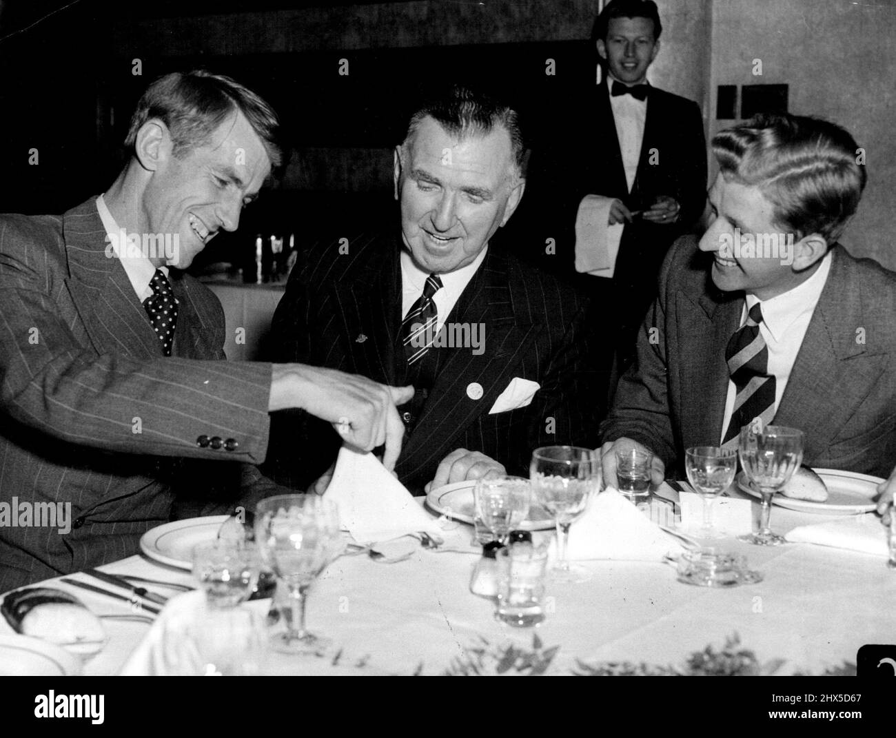 Le conquérant du Mont Everest, Sir Edmund Hillary a utilisé une serviette de table pour montrer au Premier ministre de la Nouvelle-Zélande, M. Holland, comment l'ascension a été planifiée lorsqu'ils se sont rencontrés pour la première fois au dîner à l'hôtel Australia ce soir. À droite, George Lowe est un autre membre de l'équipe d'escalade réussie. 7 août 1953. (Photo de Frank Albert Charles Burke/Fairfax Media). Banque D'Images